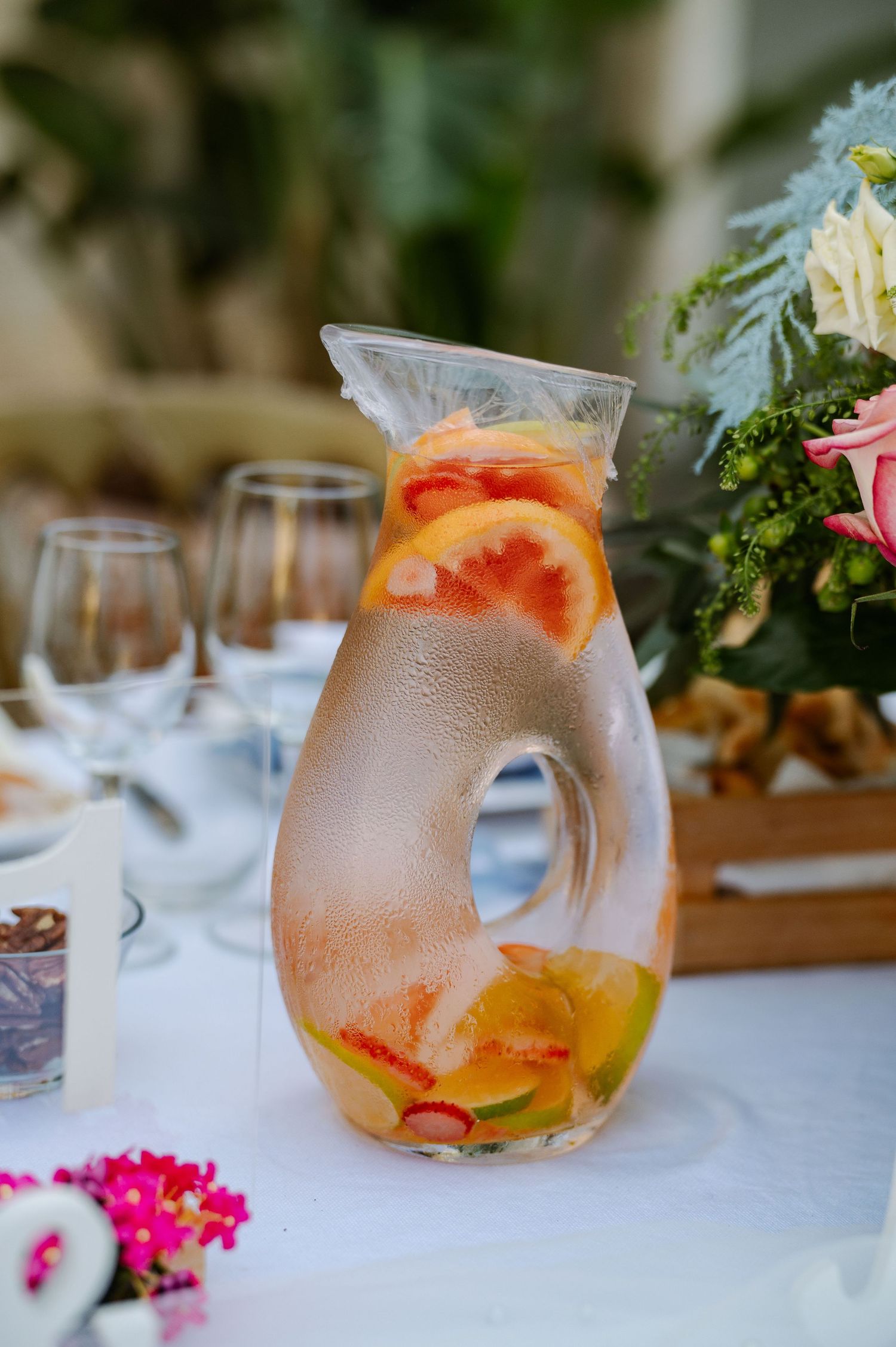 Refreshing cocktail glasses garnished with citrus slices and greenery on an elegant white tablecloth setting.