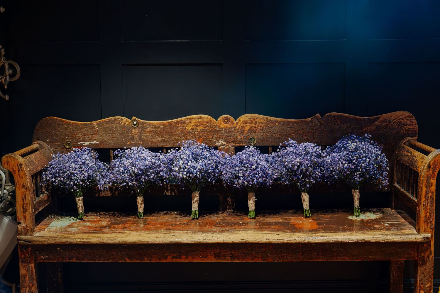 Rustic wooden bench decorated with purple lavender flowers against a dark blue background.