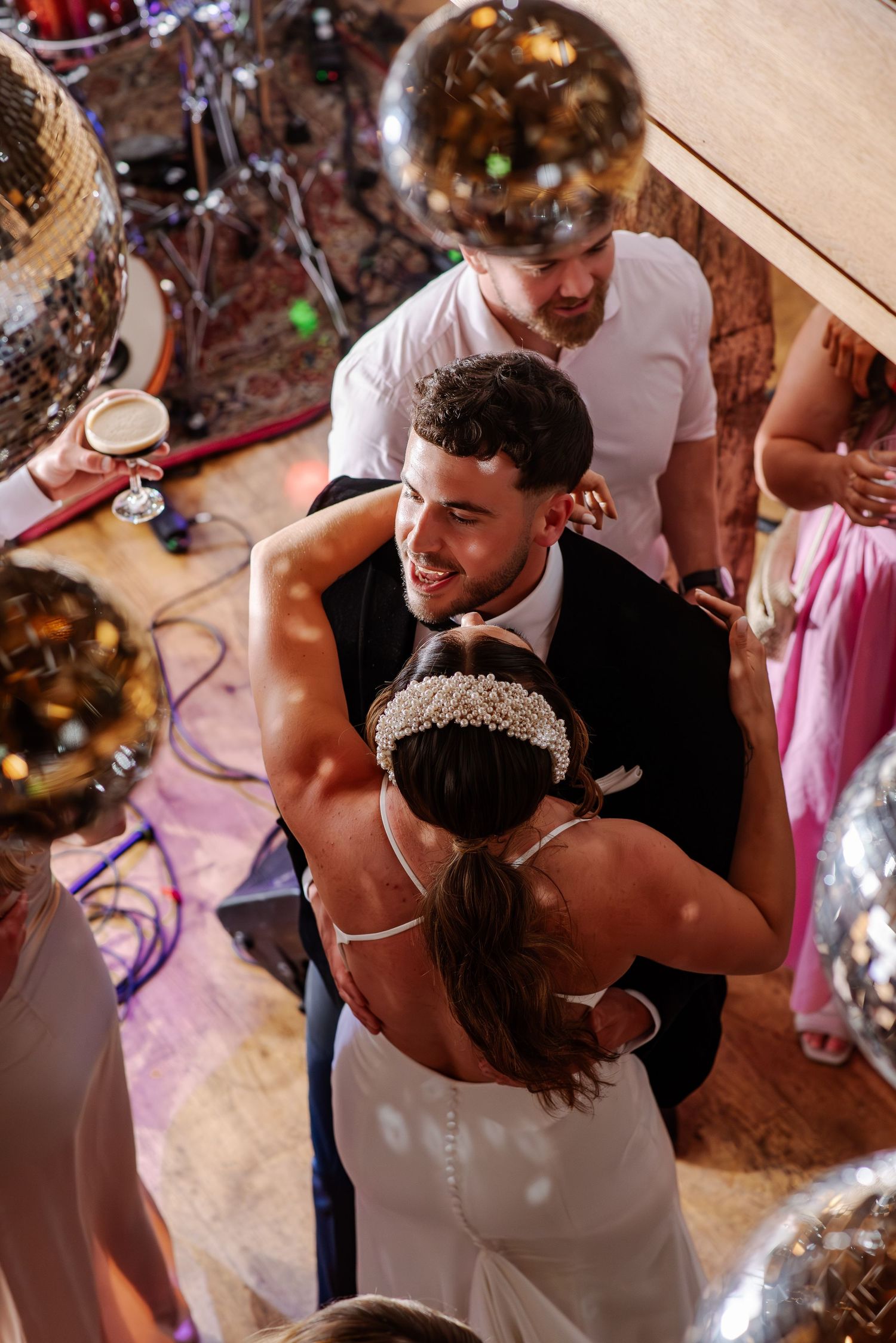 Dancing couples celebrate at a wedding reception with romantic lighting and festive atmosphere.