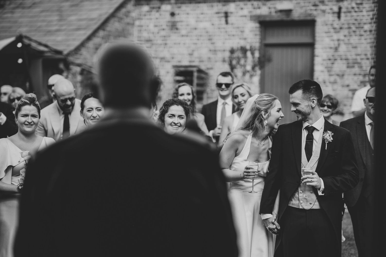 A black and white wedding reception photo shows guests dancing and celebrating together on the dance floor.