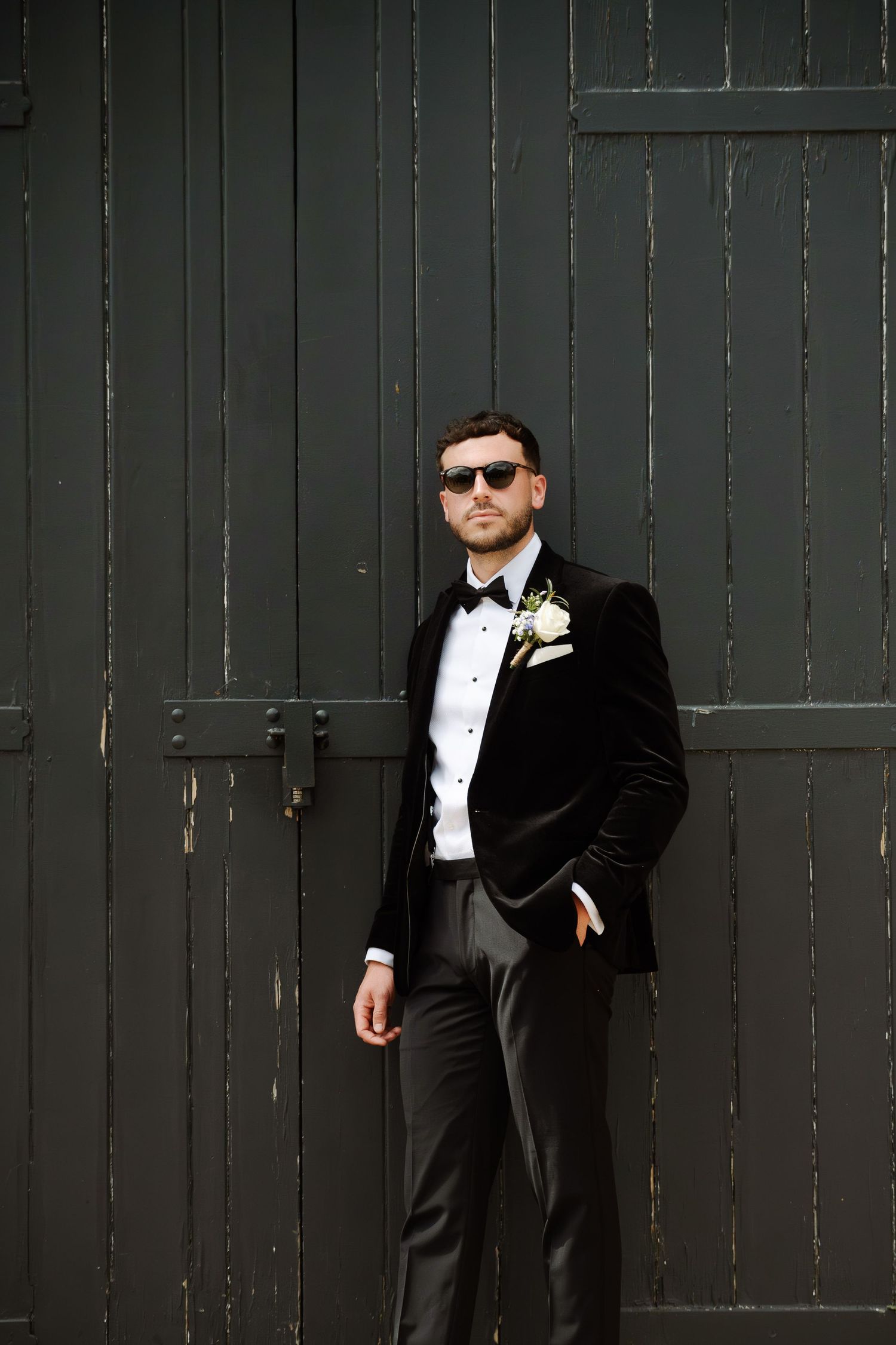Formal attire against dark wooden wall backdrop creates dramatic contrast in wedding photography.