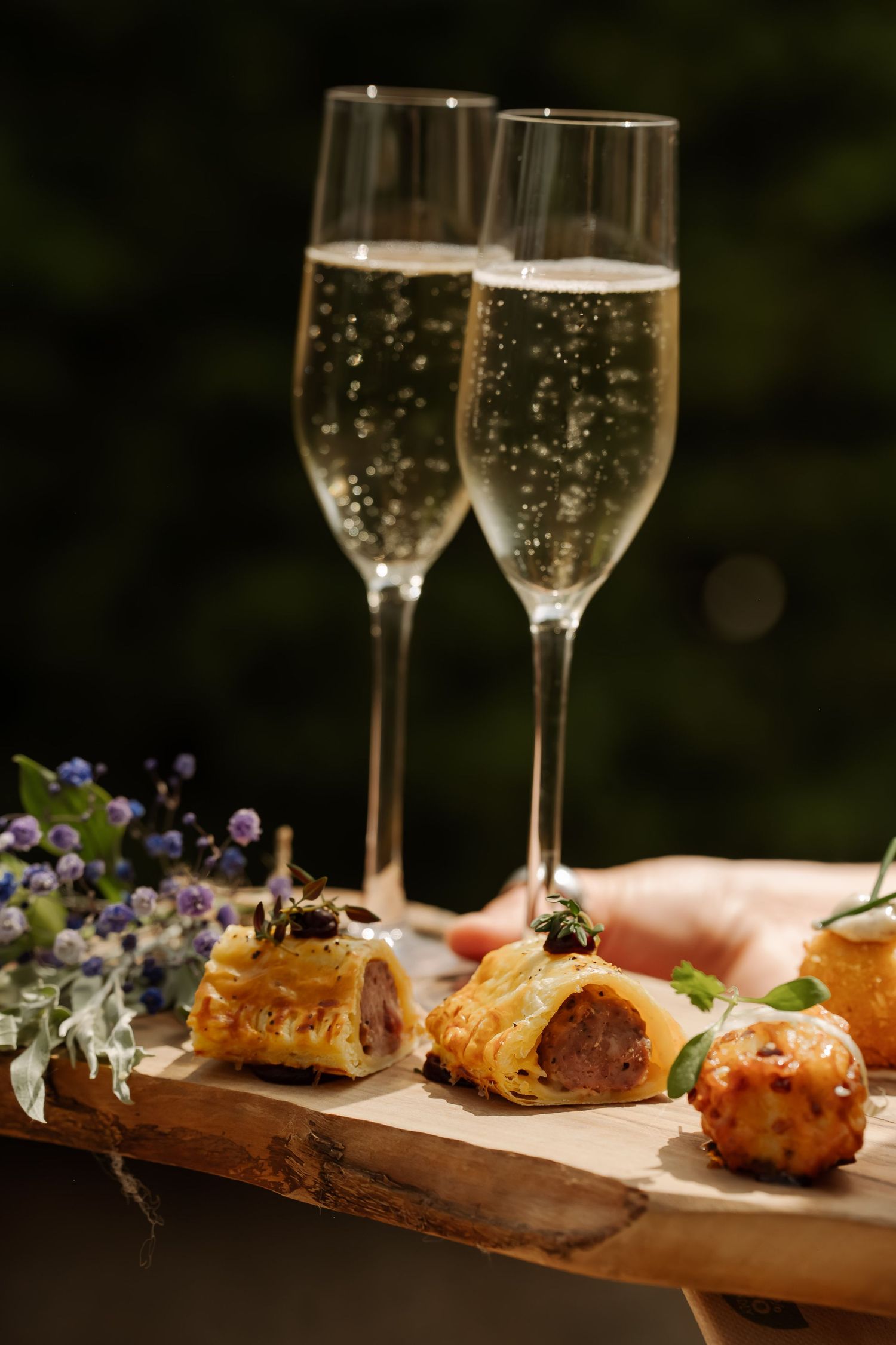 Elegant appetizers and champagne flutes displayed on a wooden serving board.
