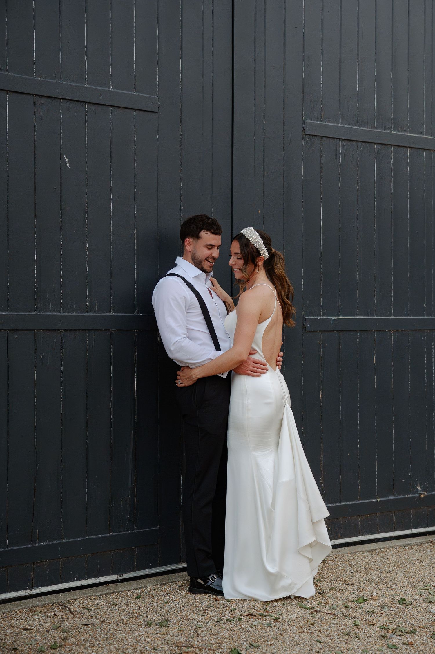 Wedding couple embracing against a dark barn wall with rustic charm.