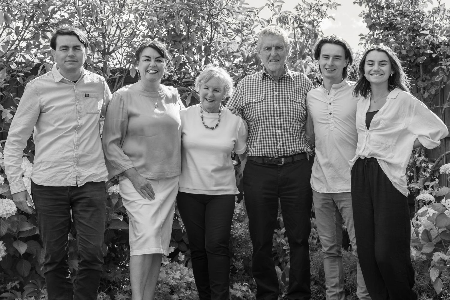 Family portrait session in garden setting with natural light. Golden hour. Relaxed candid family session. Black and white family portrait