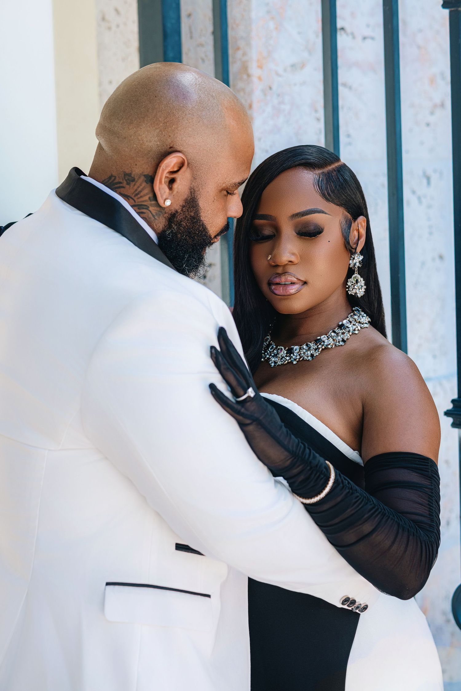 Romantic wedding couple embracing, bride in black strapless gown with sheer gloves and sparkling jewelry set.
