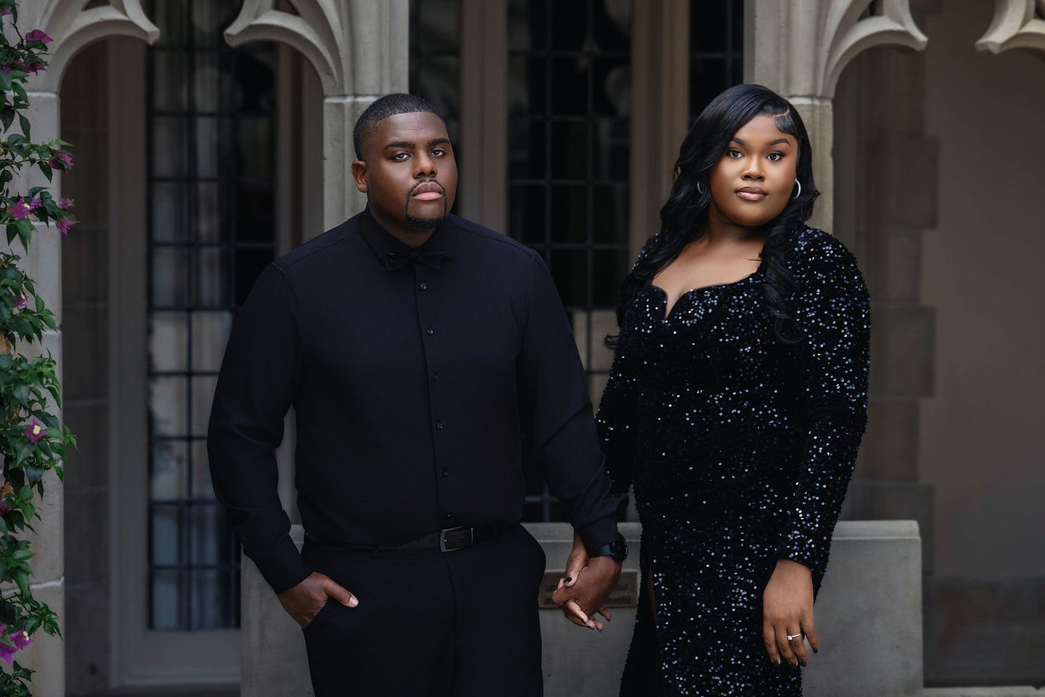 Stylish couple holding hands in black sequin and formal attire before Gothic arched stone architecture.