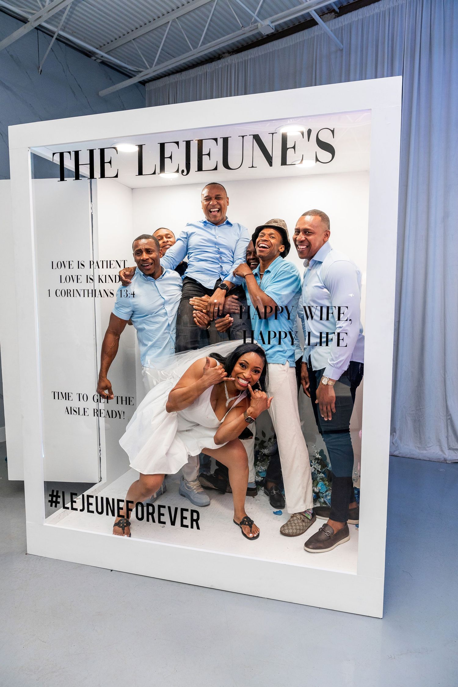 Six joyful family members pose together inside The Lejeune's custom wedding celebration photo booth frame.
