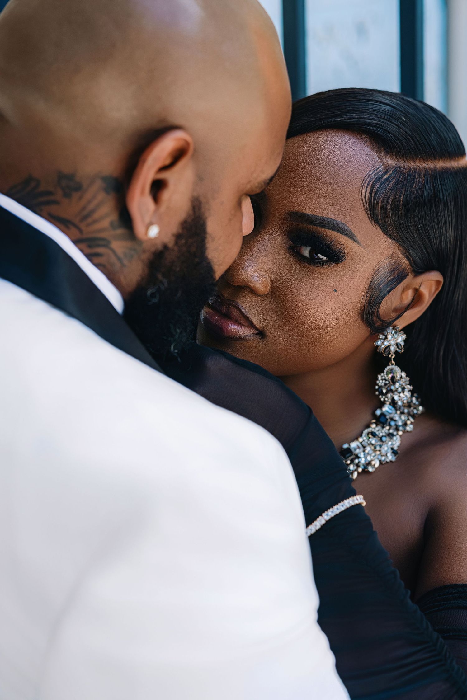 Intimate close-up of bride and groom touching foreheads, bride wearing stunning crystal earrings and necklace.