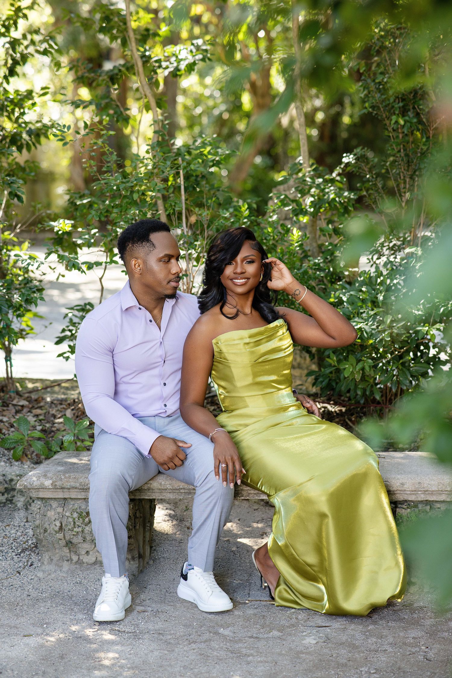 Couple sitting on stone bench, woman in gold satin gown, man in lavender shirt.