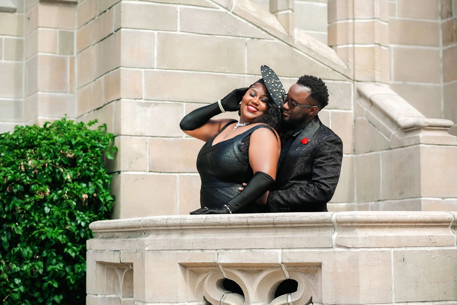 Couple sharing a romantic embrace on stone steps of a Gothic architecture building.