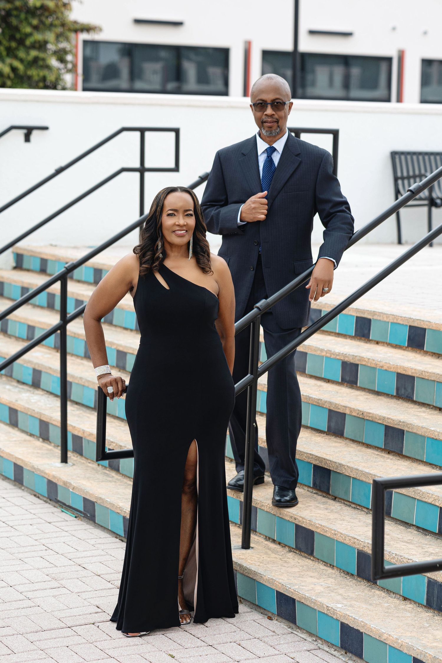 Stylish couple in black formal wear descending colorful tiled steps at an outdoor venue.