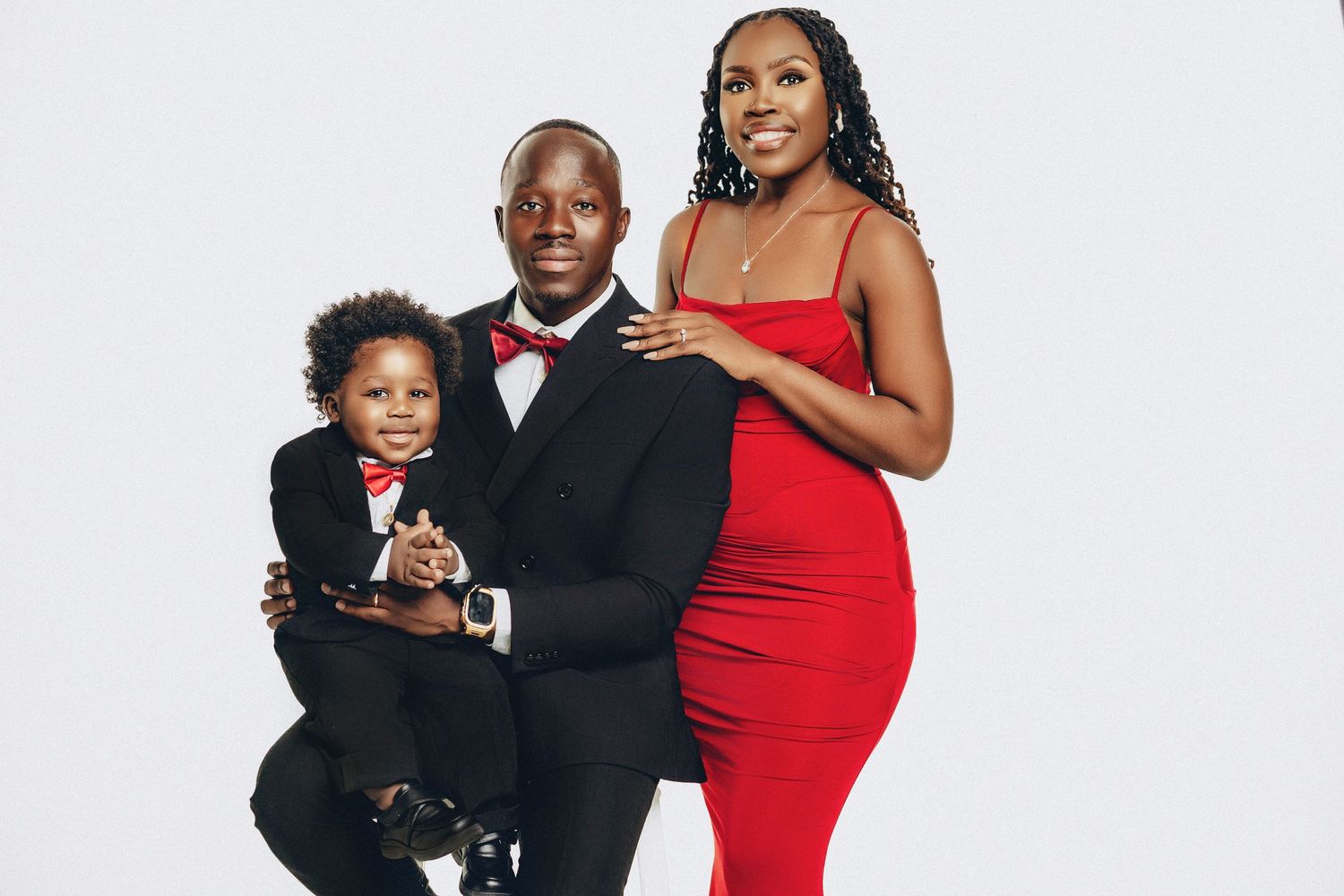 Family of three in coordinating red and black outfits posing against white studio backdrop.
