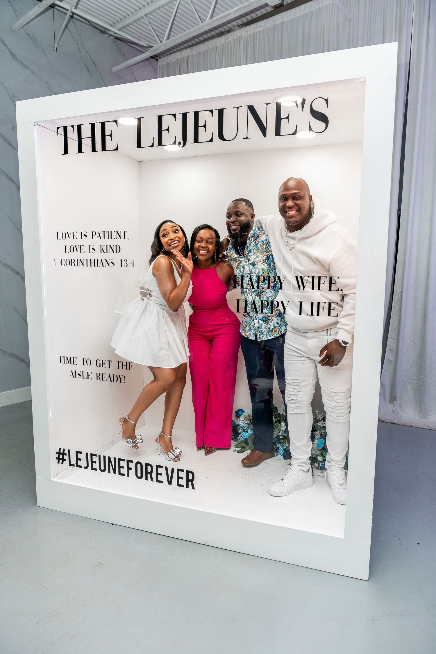 Four friends smile and pose together inside The Lejeunes LejeuneForever decorative photo frame at an event.