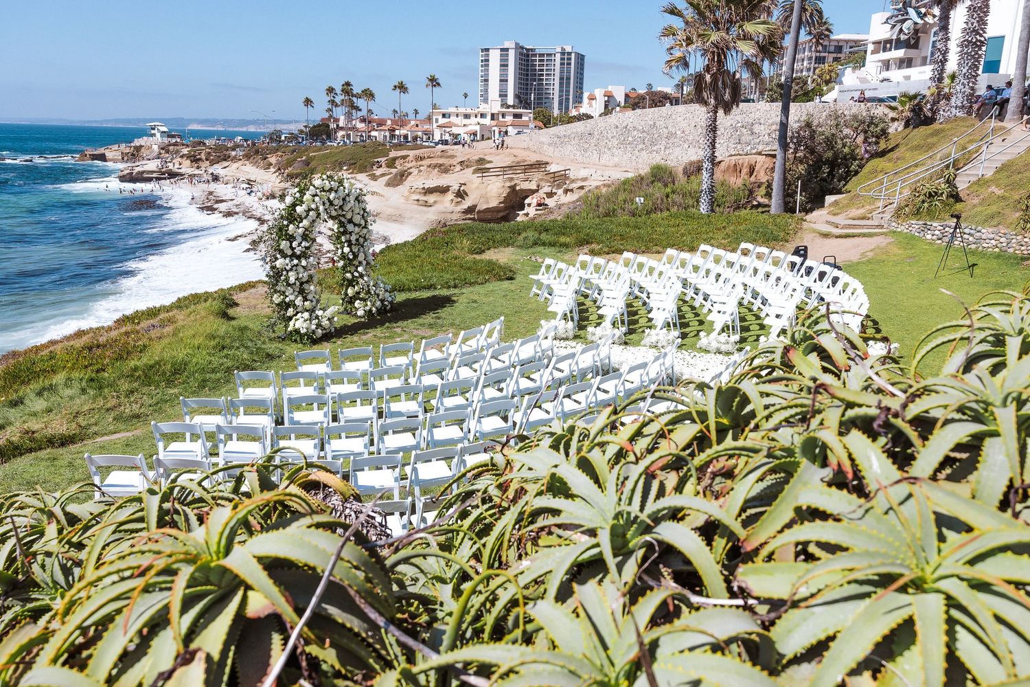 Outdoor wedding ceremony setup with white chairs overlooking a scenic California coastline with ocean views.
