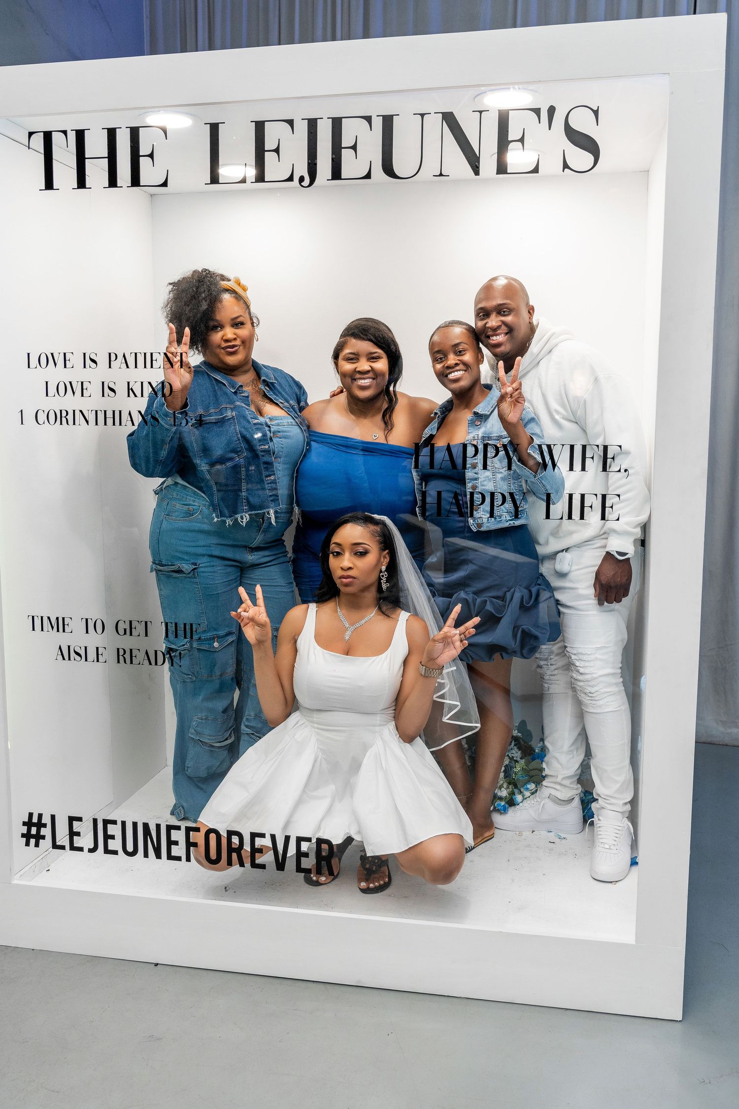 Group of five family members strike peace signs inside The Lejeune's wedding celebration photo booth frame.