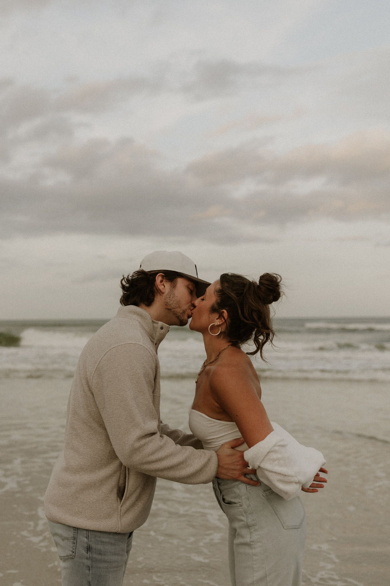 Romantic beach photoshoot sequence with couple embracing by the ocean at sunset in Ponce inlet beach Florida