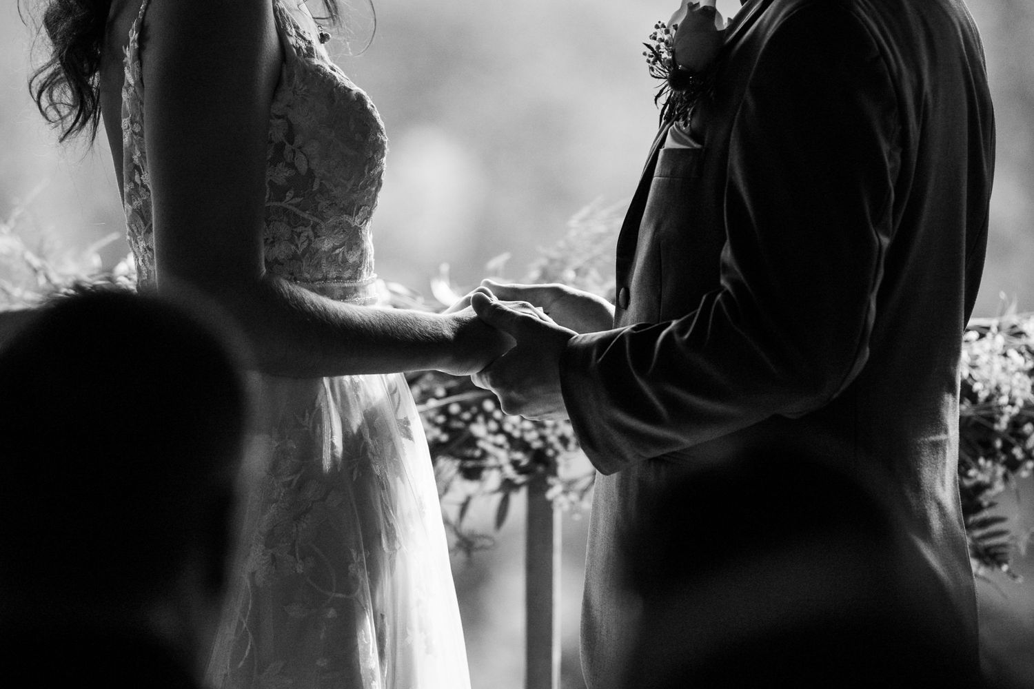 Photo de cérémonie de mariage en noir et blanc montrant le couple échangeant les alliances lors d’un moment intime à l’autel.