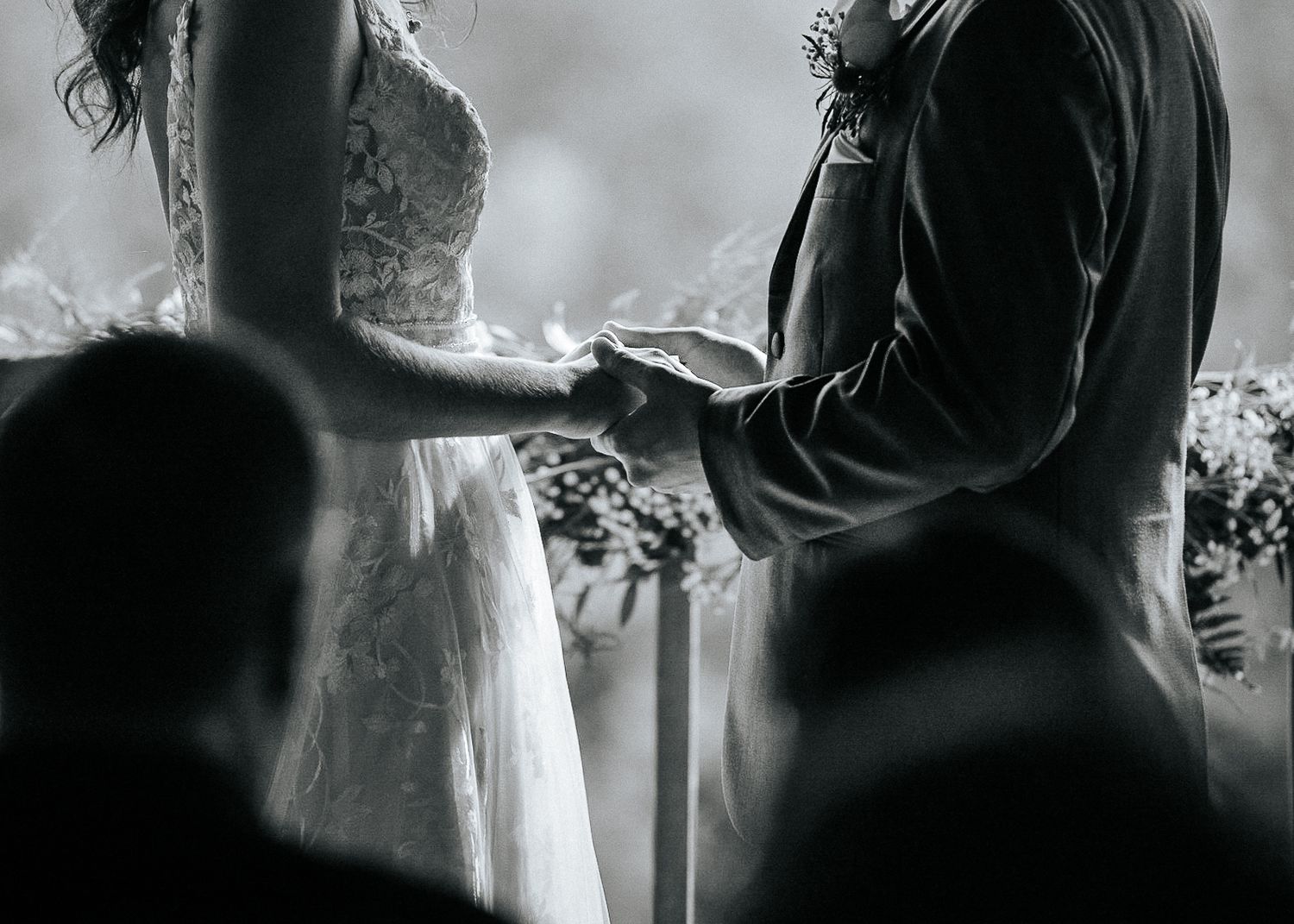 Gros plan en noir et blanc d'un couple échangeant des alliances lors d'une cérémonie de mariage en plein air.