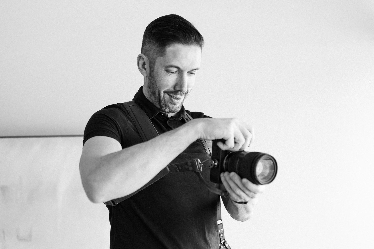 Un photographe pro en t-shirt noir examine des images sur l’écran de son appareil photo en studio.