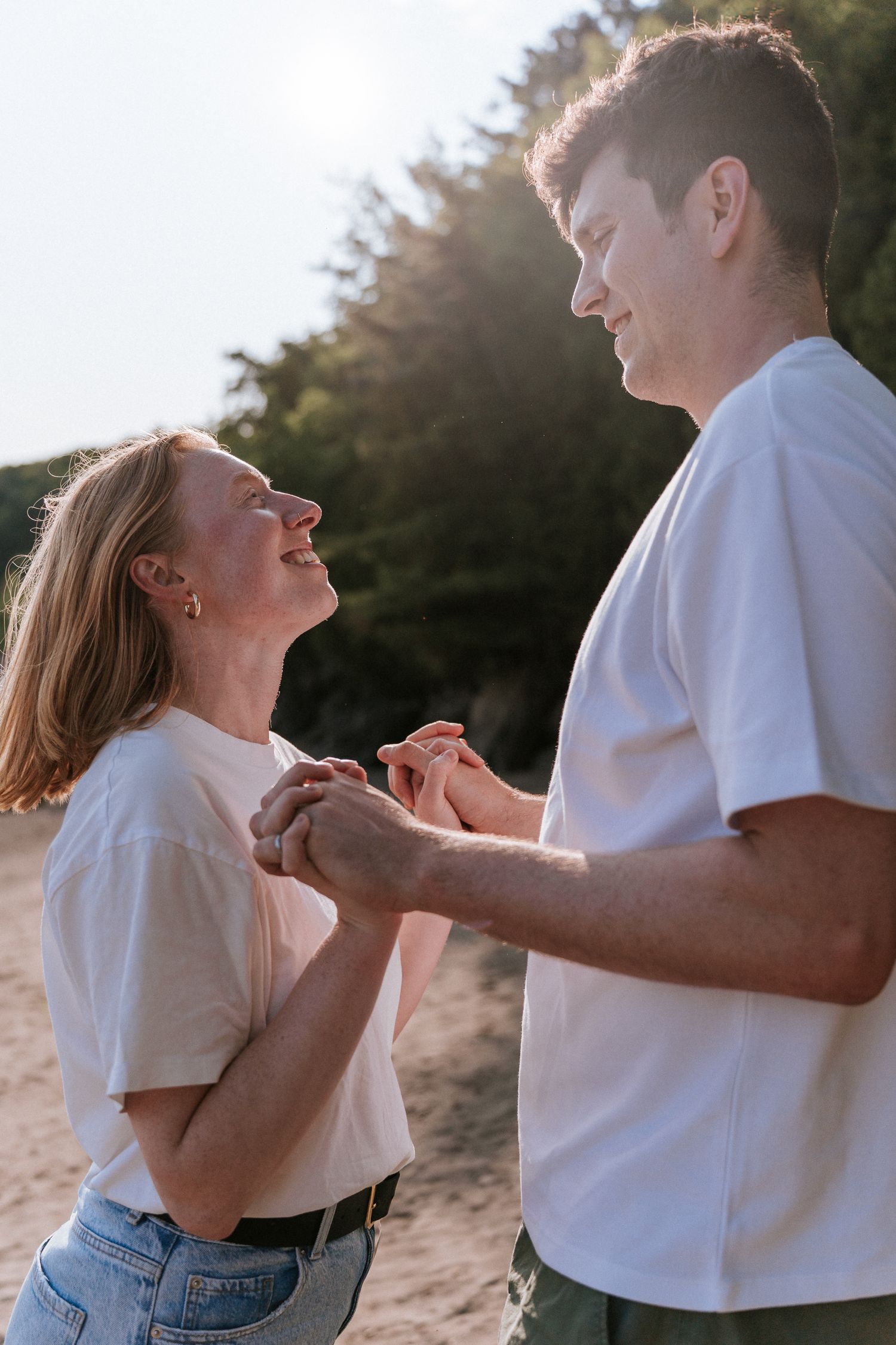 Un couple en t-shirts blancs partage un joyeux moment pris sur le vif, ensemble, en plein air pendant l'heure dorée.