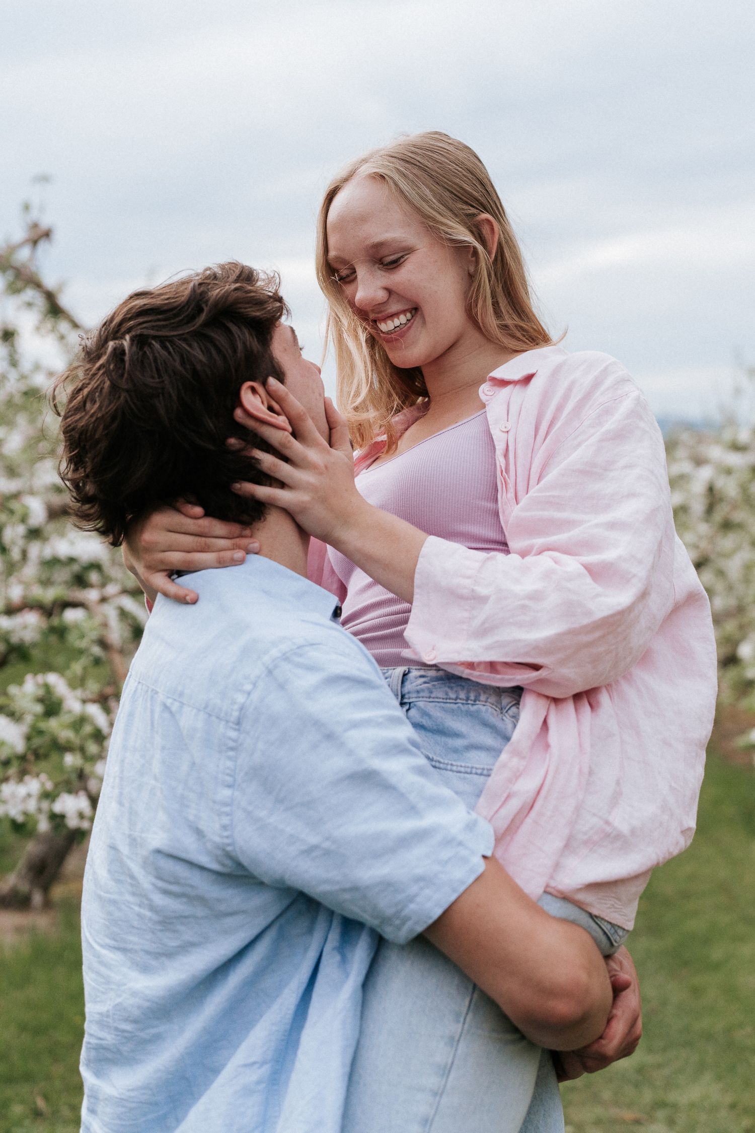 Un couple s'enlace et profite d'un moment enjoué dans un verger en fleurs au printemps.