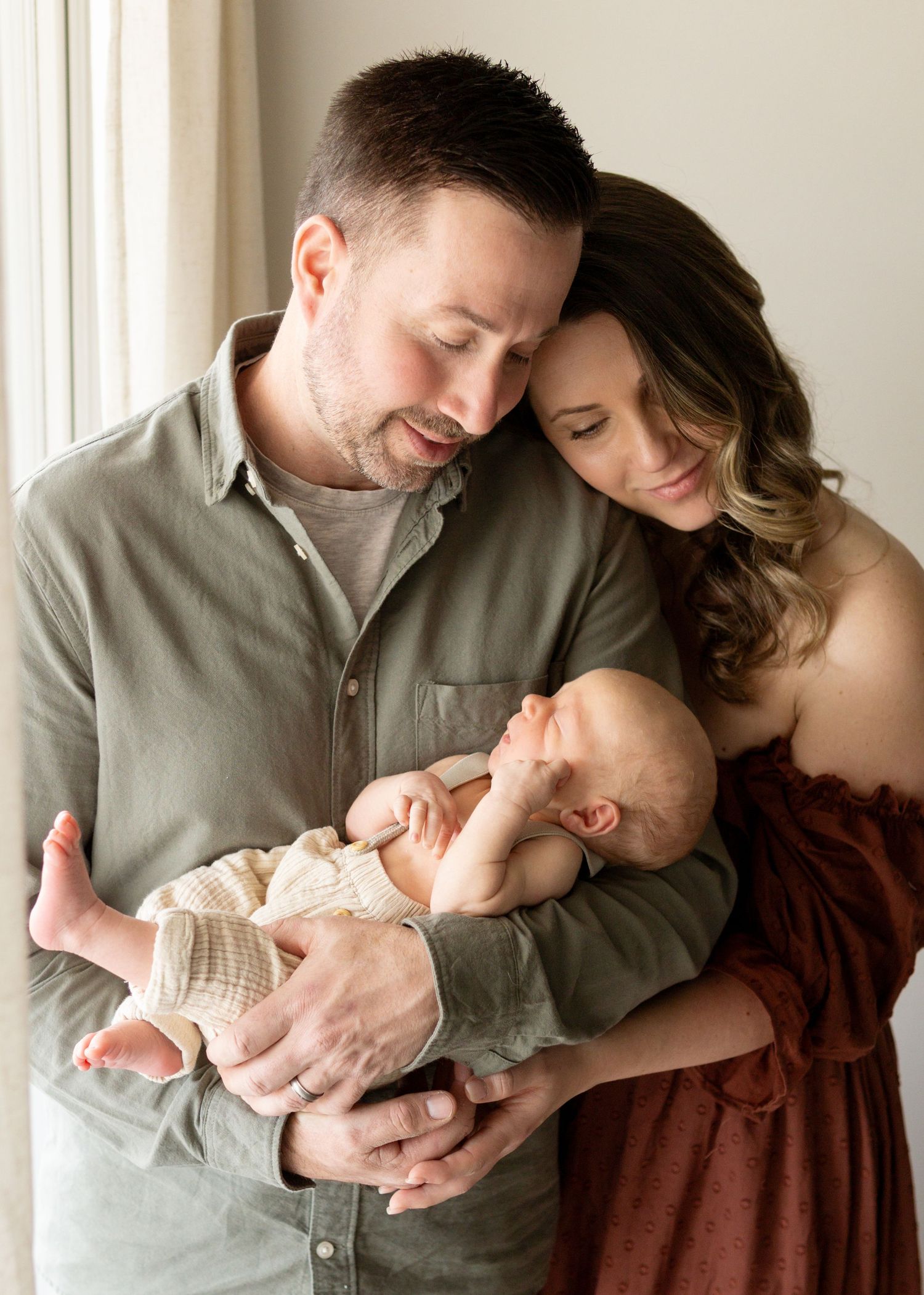 Family cuddling their newborn during an in-home newborn photography session in Cherry Hill NJ.