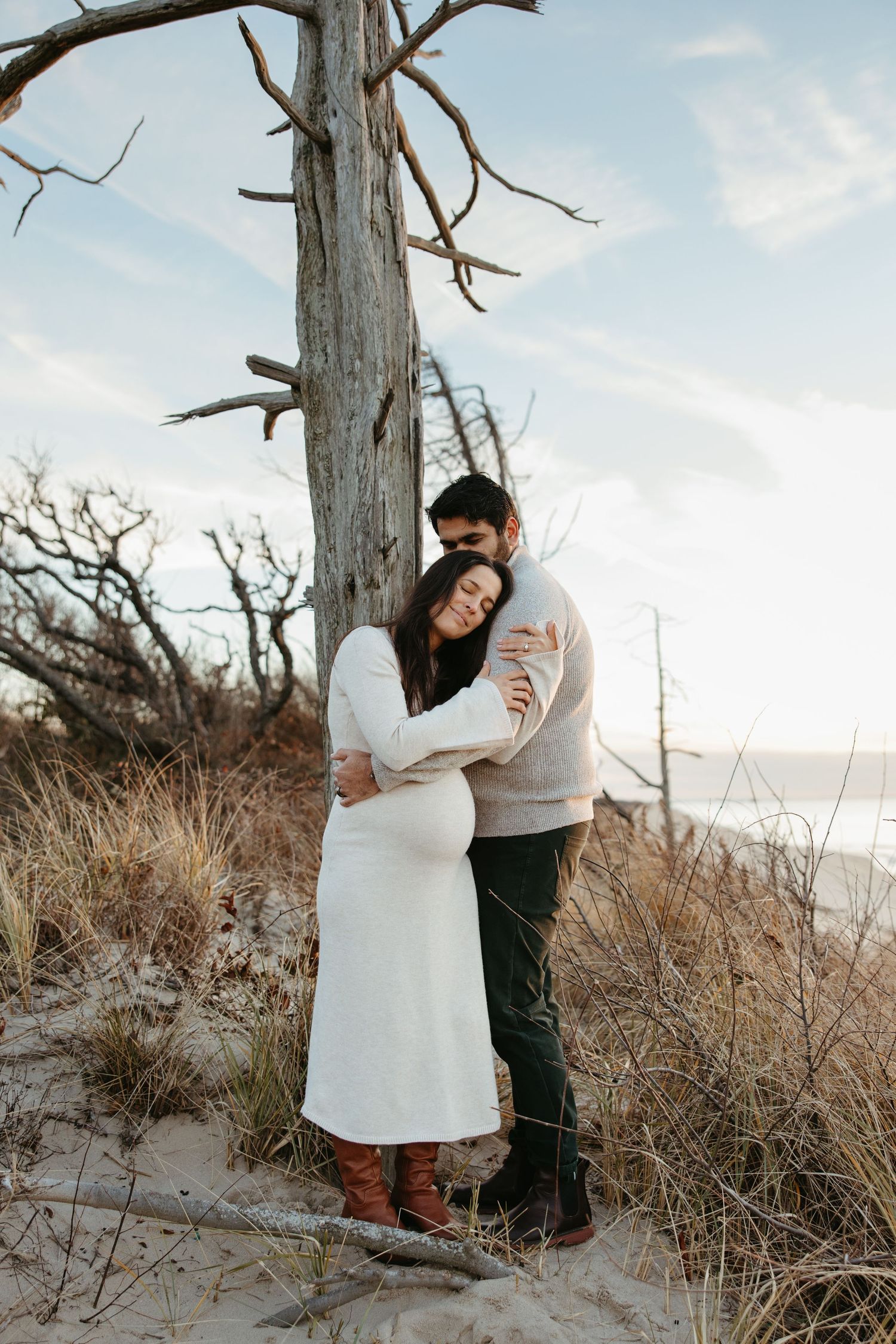 First-time parents embracing during their winter beach maternity session in Cape May, NJ.