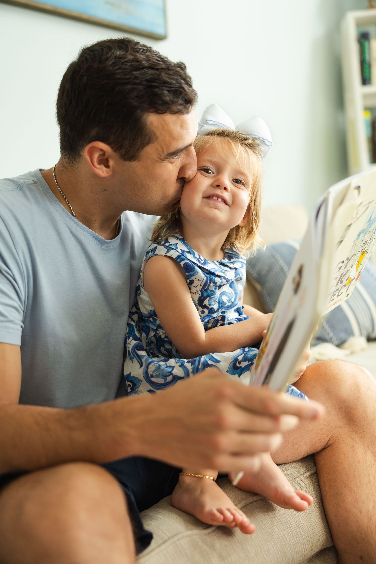 A sweet family bonding moment on the couch while reading and sharing kisses together.