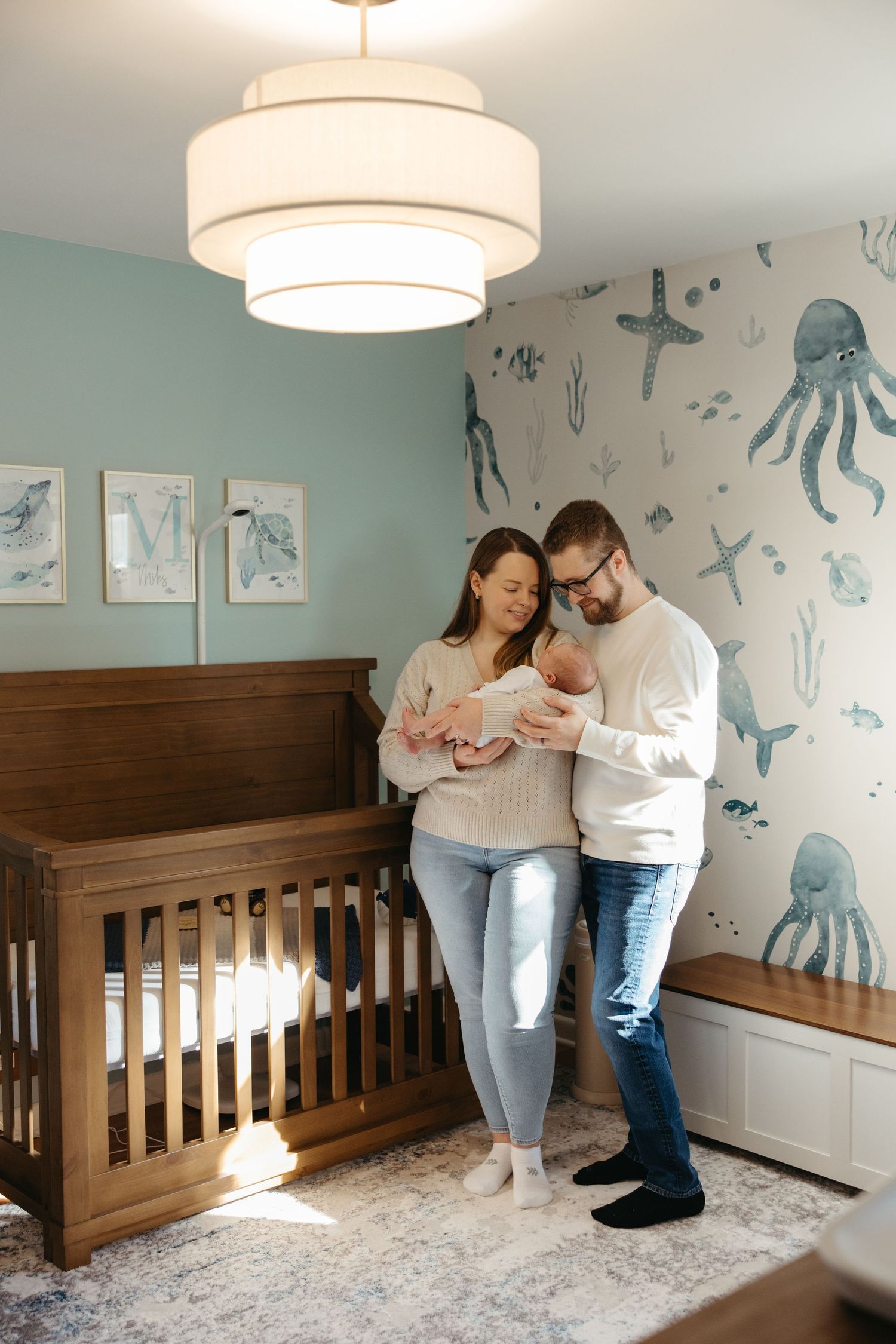 Lifestyle newborn session in Cherry Hill NJ featuring parents holding their baby in a nursery by a South Jersey newborn photographer