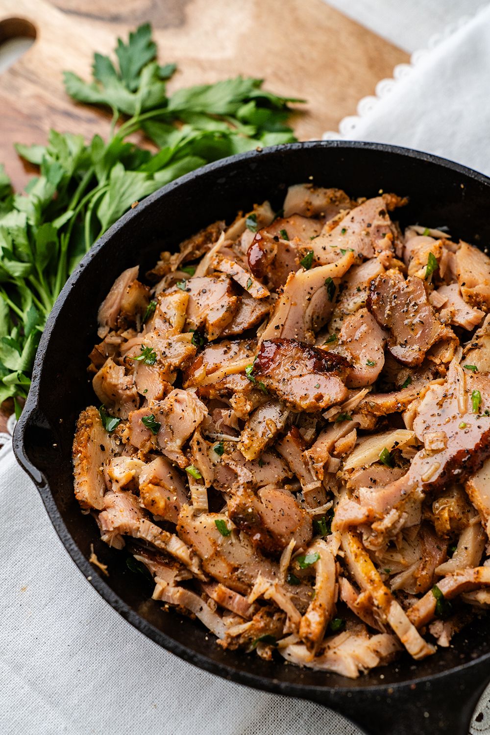 Sizzling Korean BBQ pork belly slices garnished with fresh herbs served in a cast iron skillet.