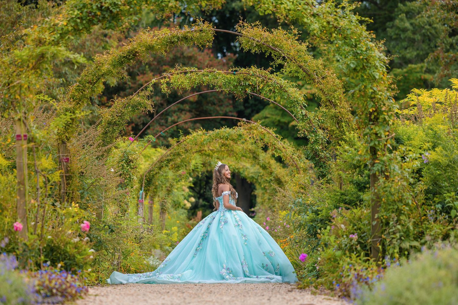 Lush garden path with green foliage and a light blue structure visible in the background.