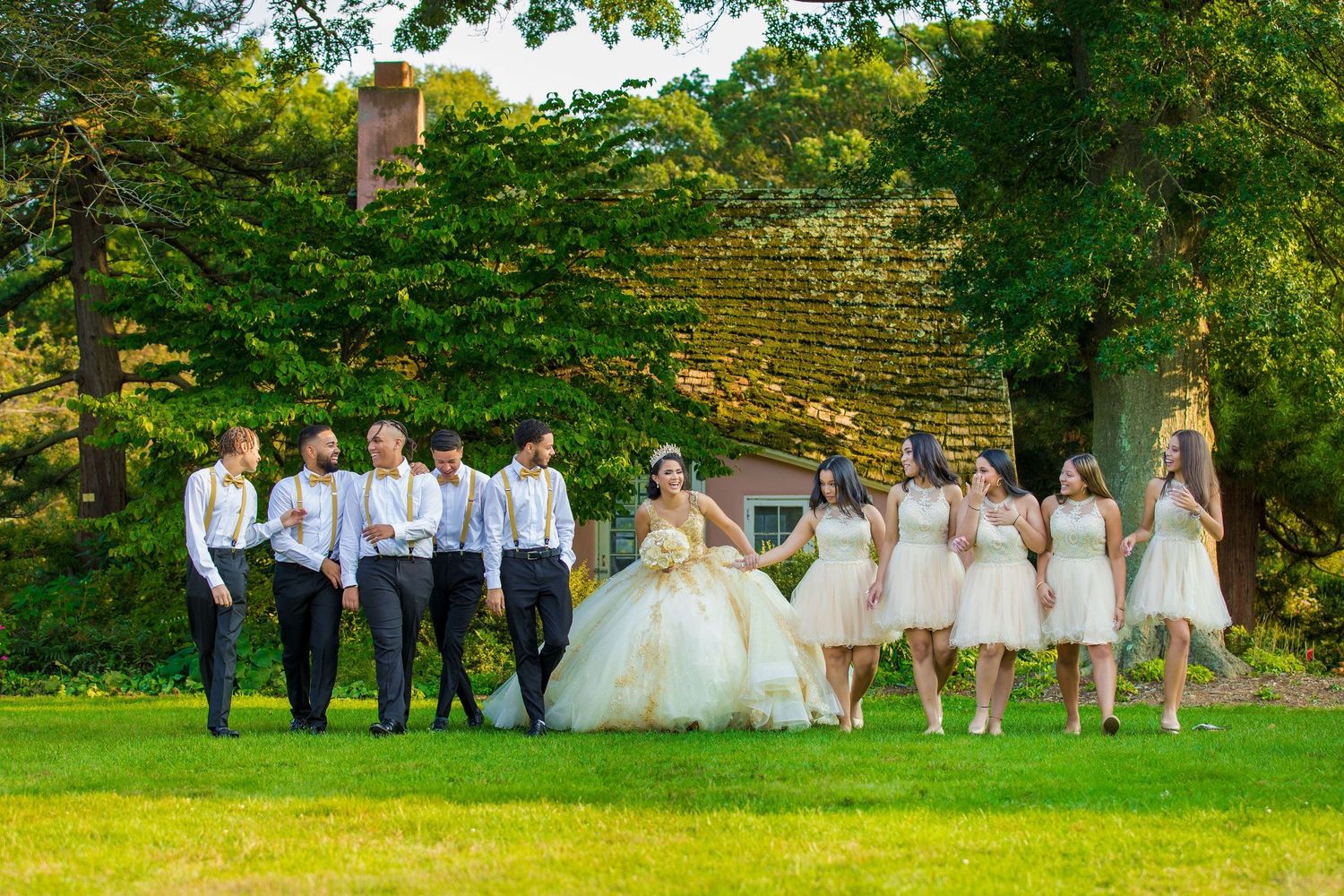 Wedding party poses for fun group photos in a lush garden setting during golden hour.