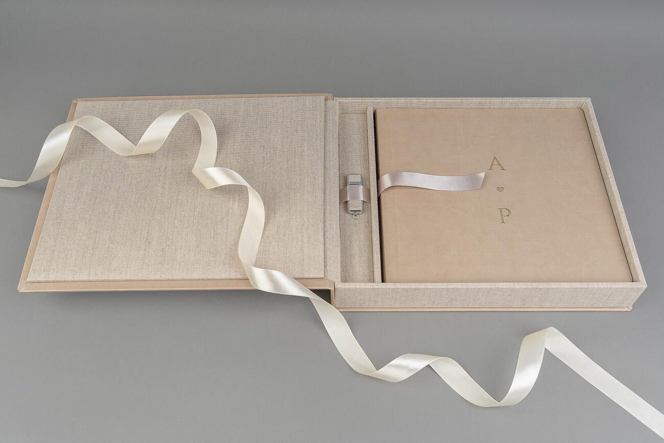 Multiple pages of a light-colored fabric or textile book sample lying flat on a gray surface.