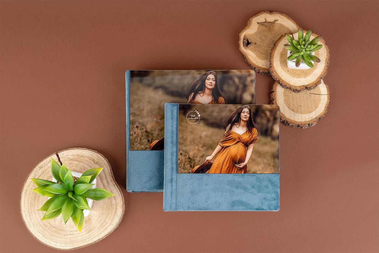 Decorative wooden slice coasters with green leaf accents arranged on brown surface with photos displayed in background.
