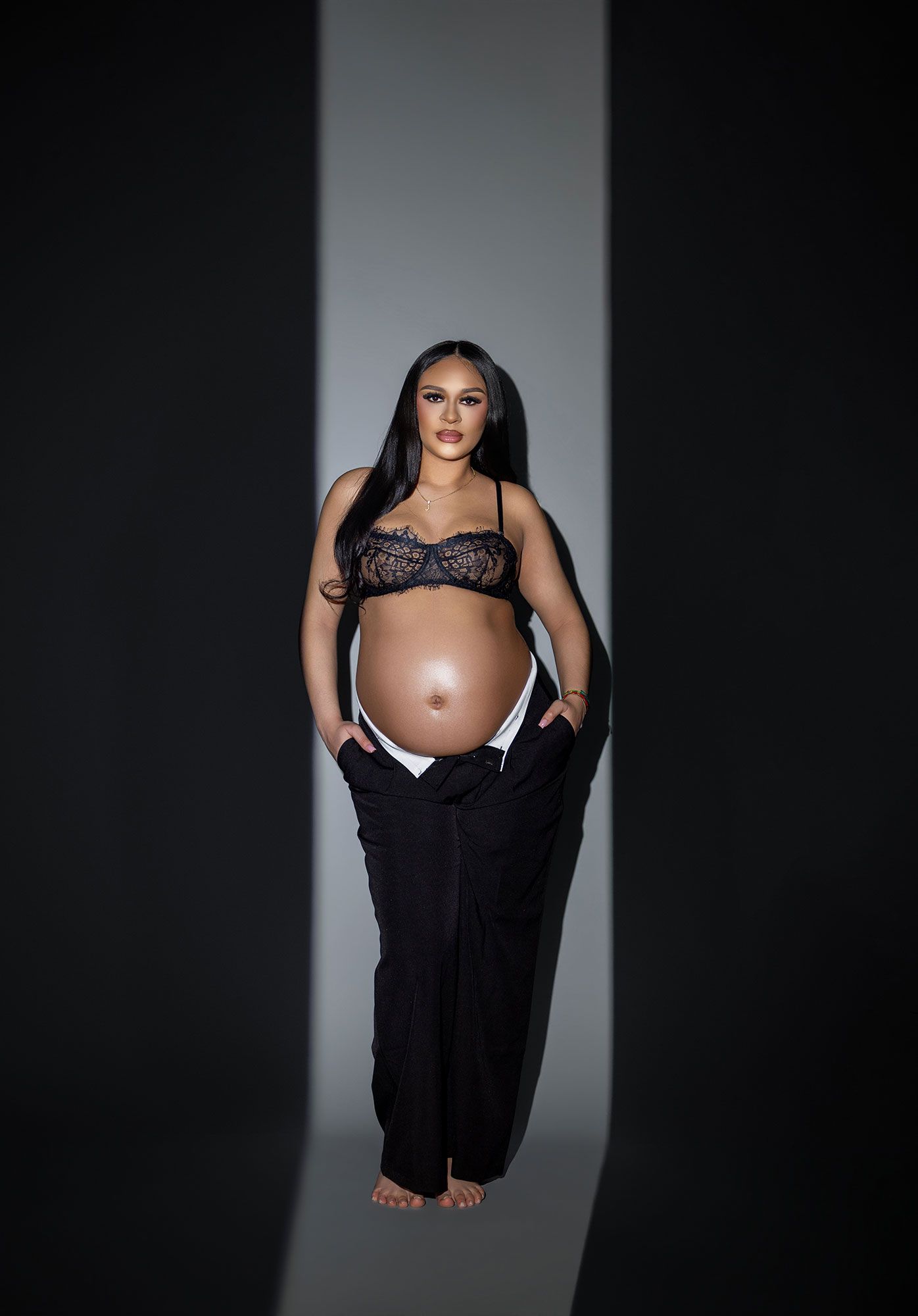 A series of dramatic black and white maternity photos showing a pregnant figure in dark clothing against a stark backdrop.