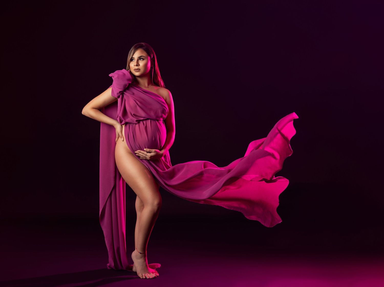 A series of artistic dance poses in flowing hot pink fabric against a dark background.