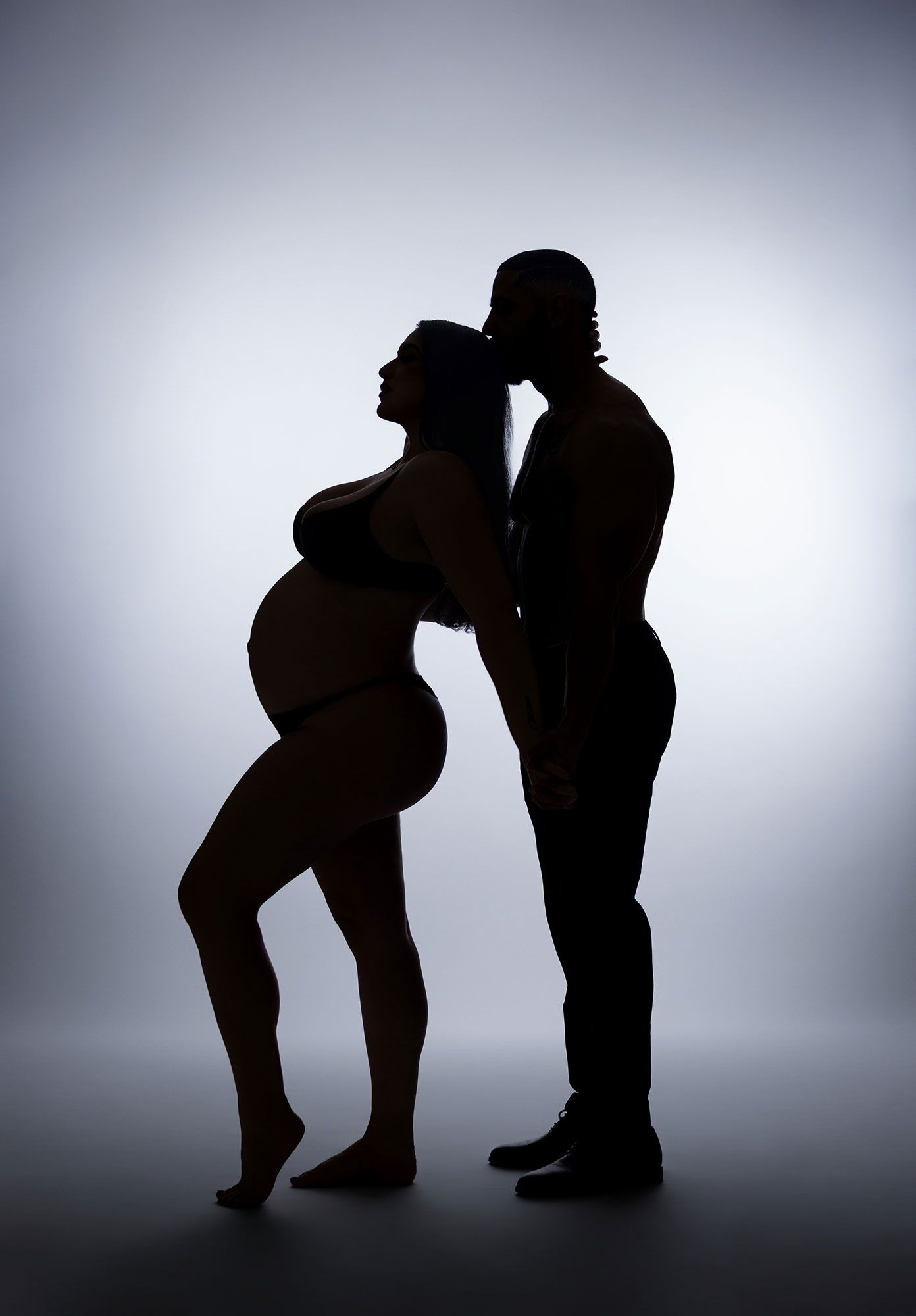 Silhouette sequence showing progressive stages of pregnancy and fetal development against a backlit gradient background.