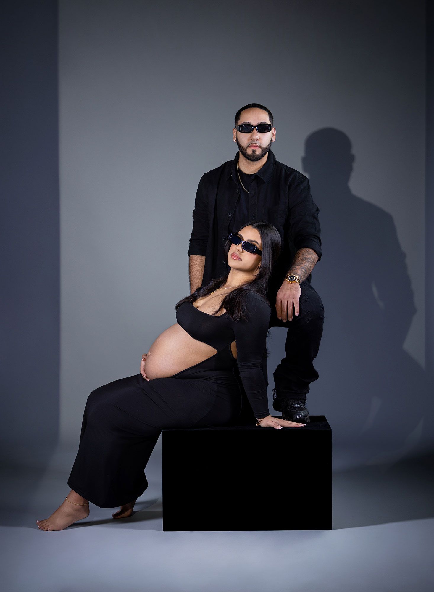 Artistic maternity photo series showing silhouettes and poses against a gray studio backdrop in black clothing.