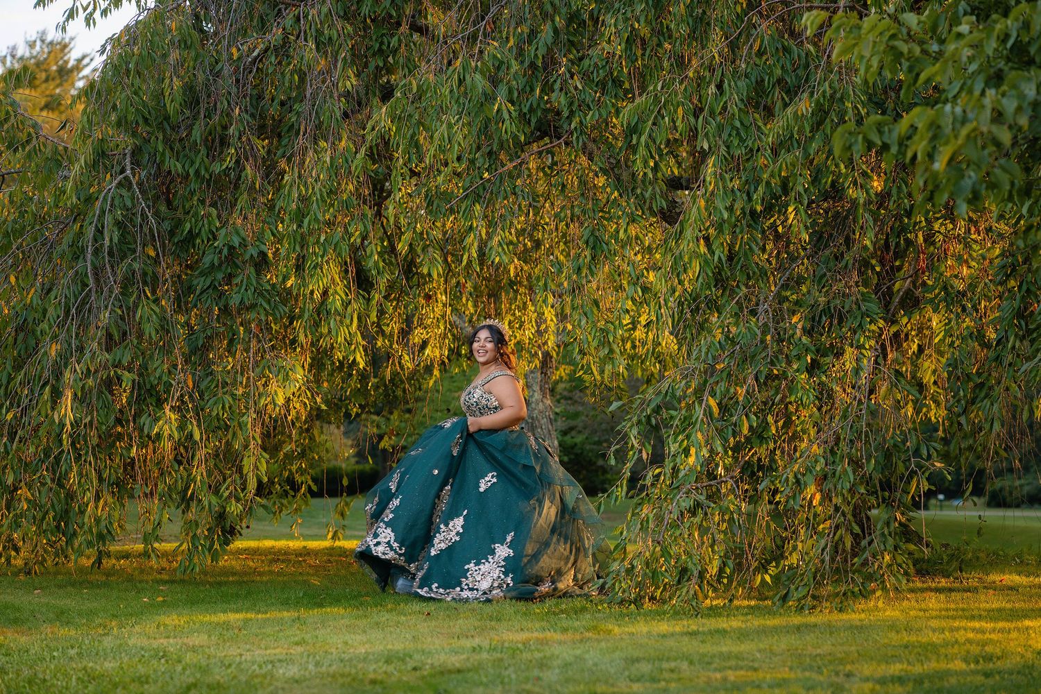 A blue dress creates a striking contrast against autumn foliage in a garden setting.