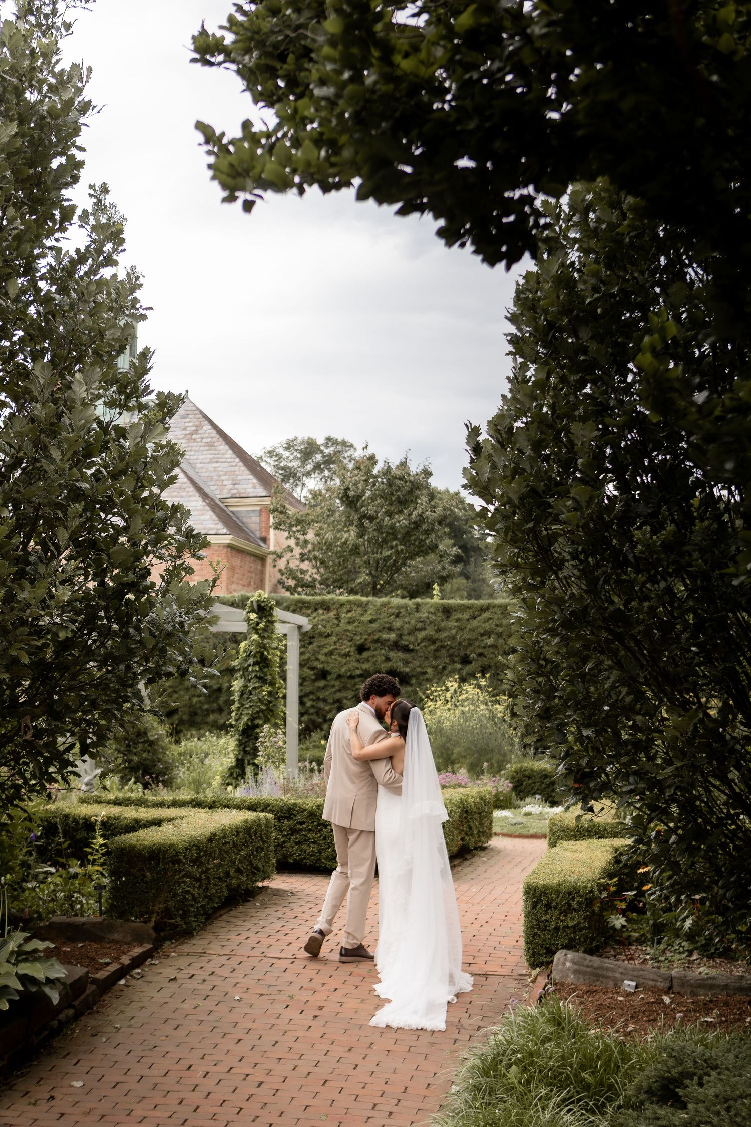 Bride and groom kissing while walking up brick path in a garden in Mansfield Ohio