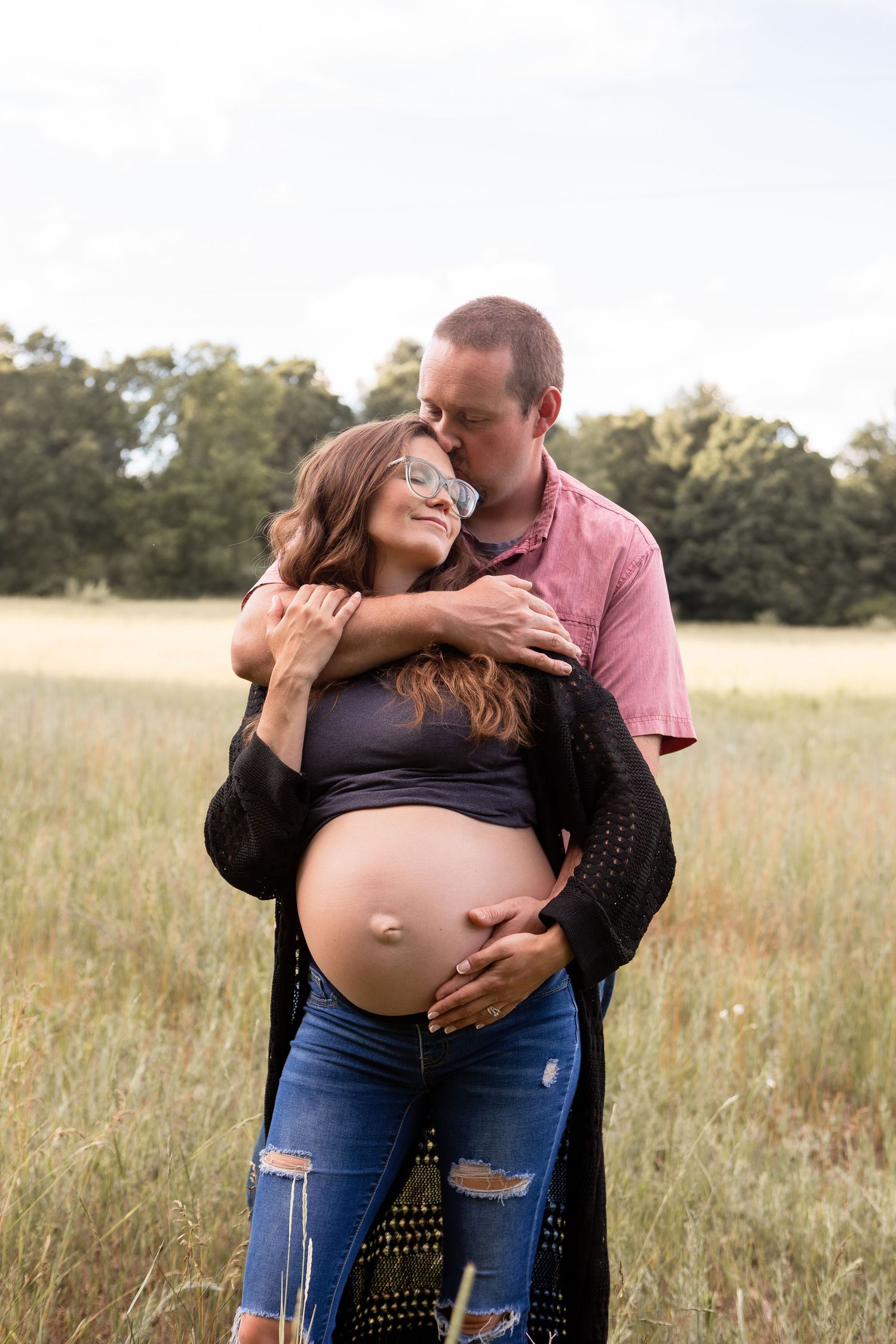 Pregnant woman and husband embracing for maternity photos in a wheat field in Columbus Ohio