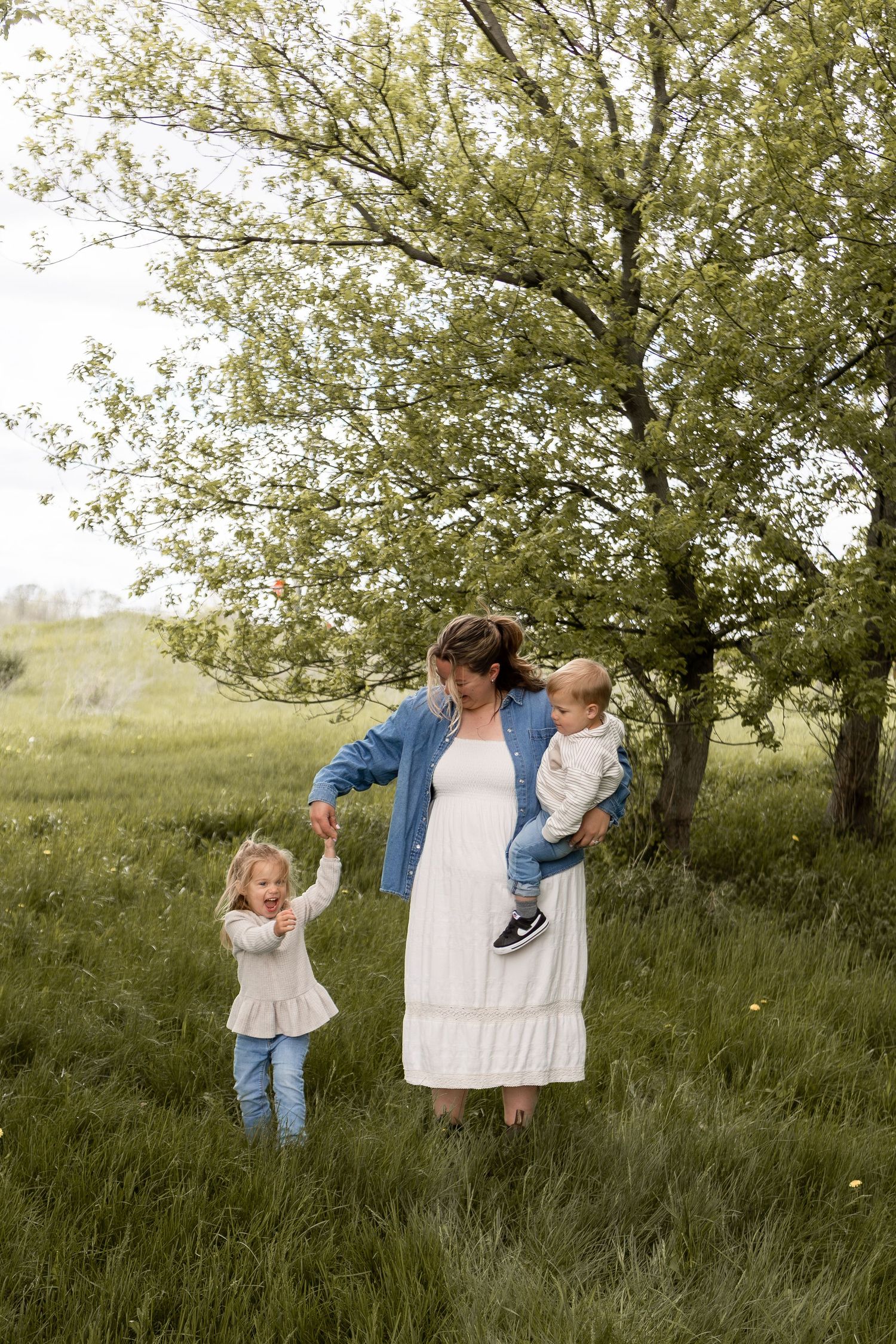 Mother and two children standing in a field twirling around in spring in Columbus Ohio