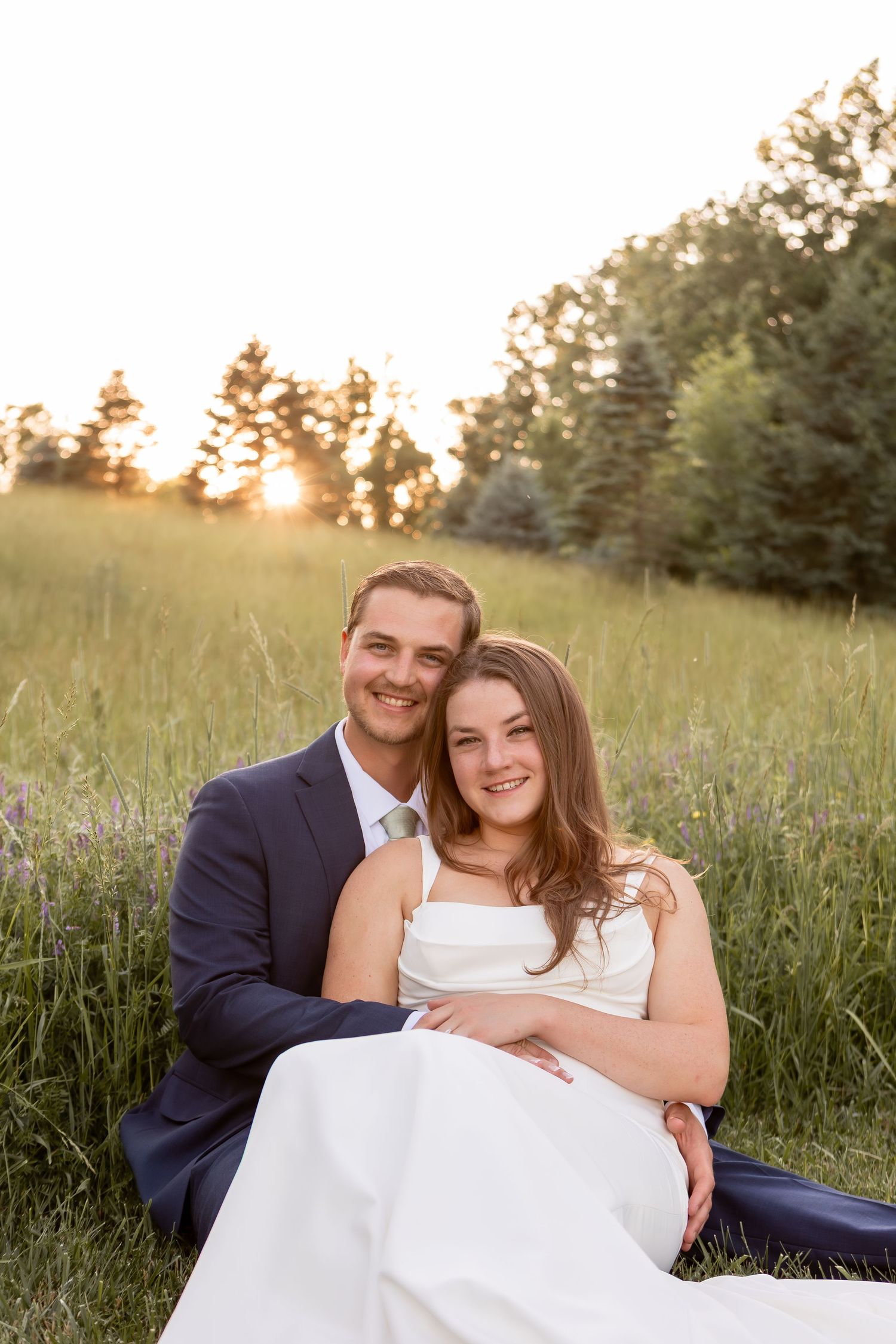 Bride sitting in groom's lap in grassy field in Columbus Ohio