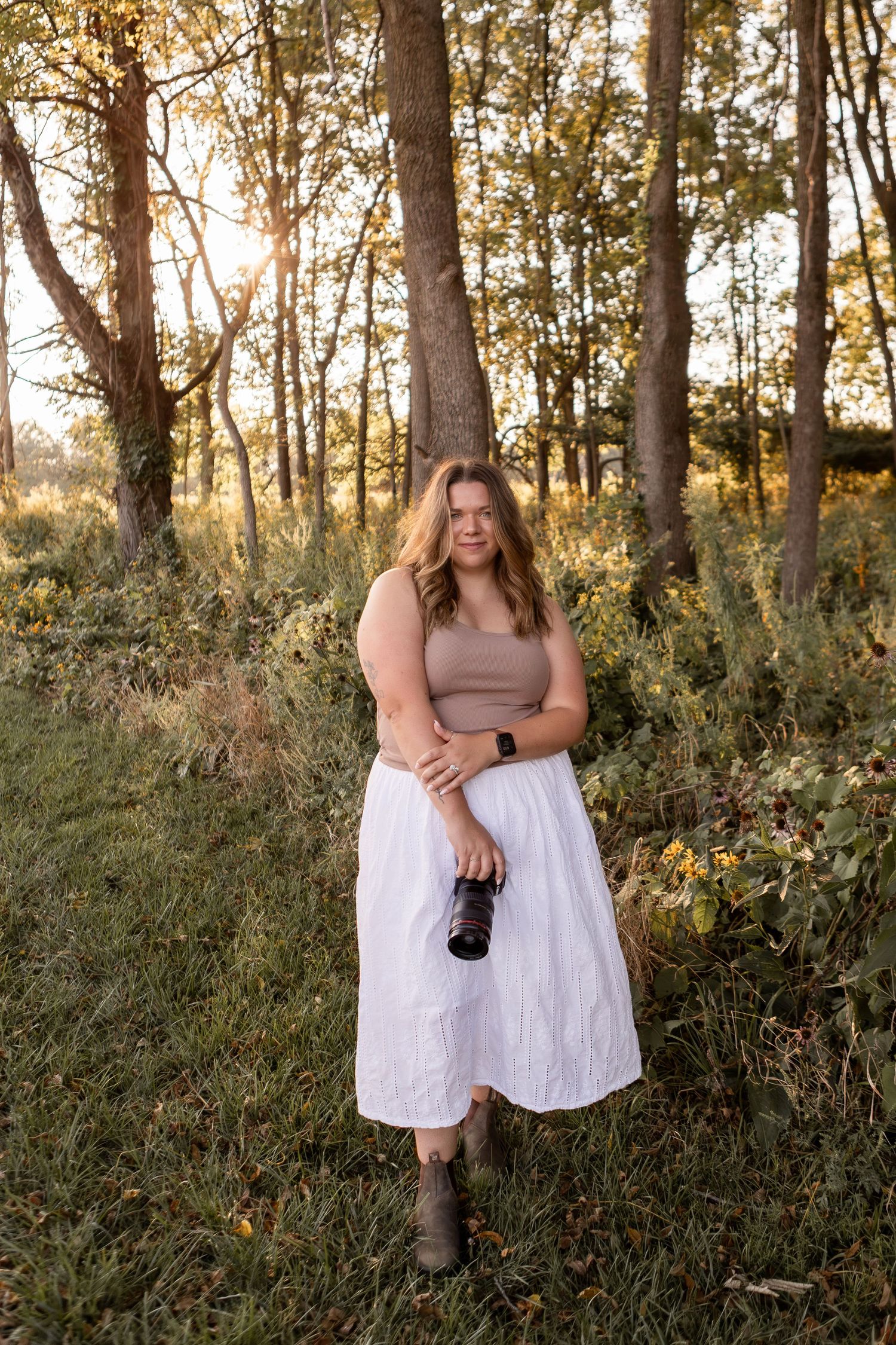 Woman holding camera standing in forest at sunset in Columbus Ohio