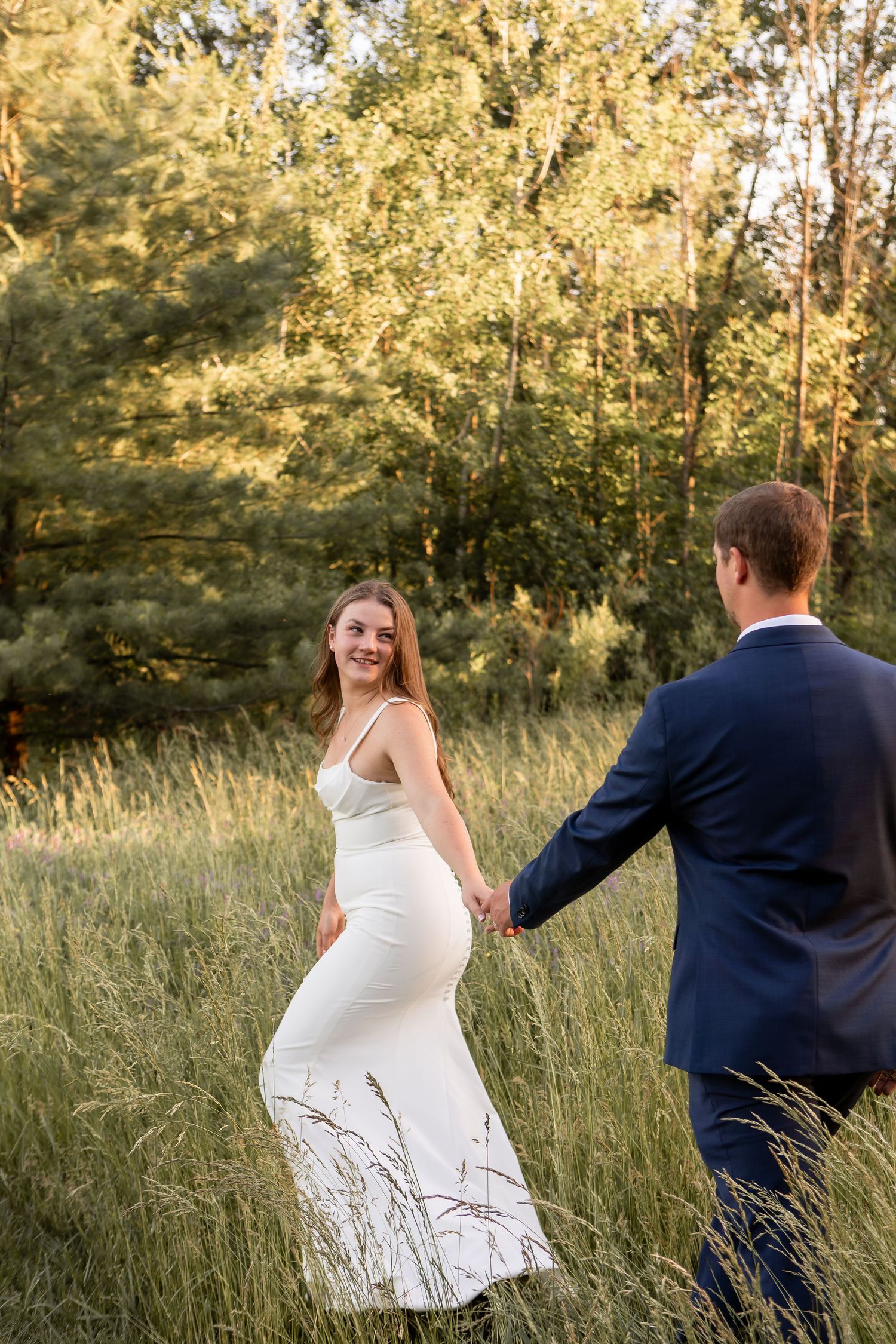 Bride holding grooms hand walking and smiling in grassy field in Columbus Ohio