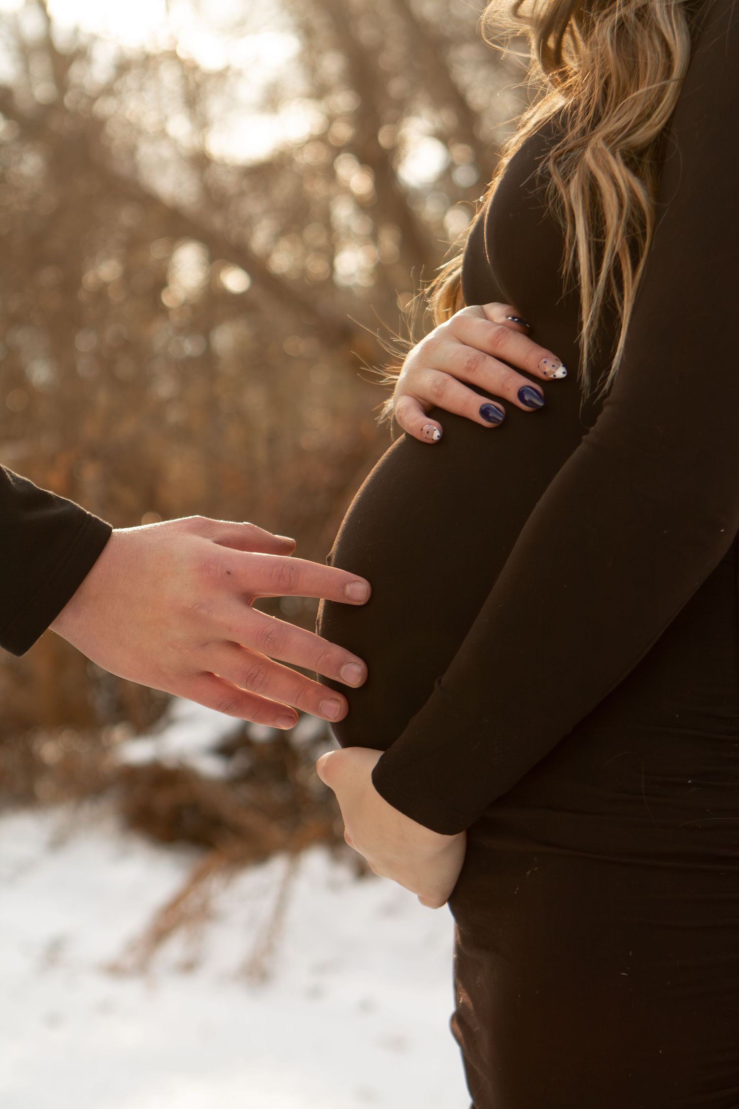 Father touching baby bump while mother holds bump in winter in Columbus Ohio
