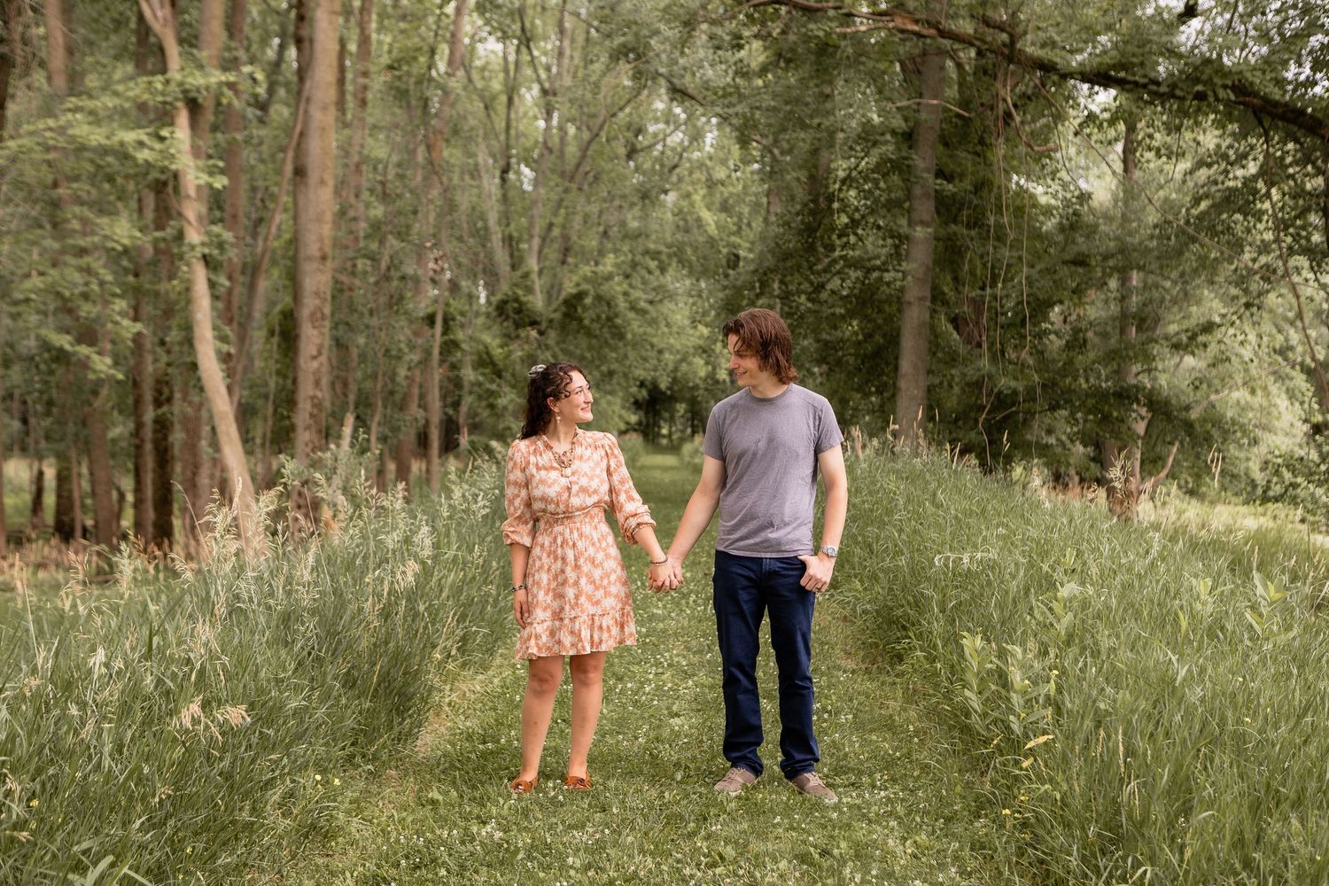 Couple standing side by side holding hands in forest in Columbus Ohio
