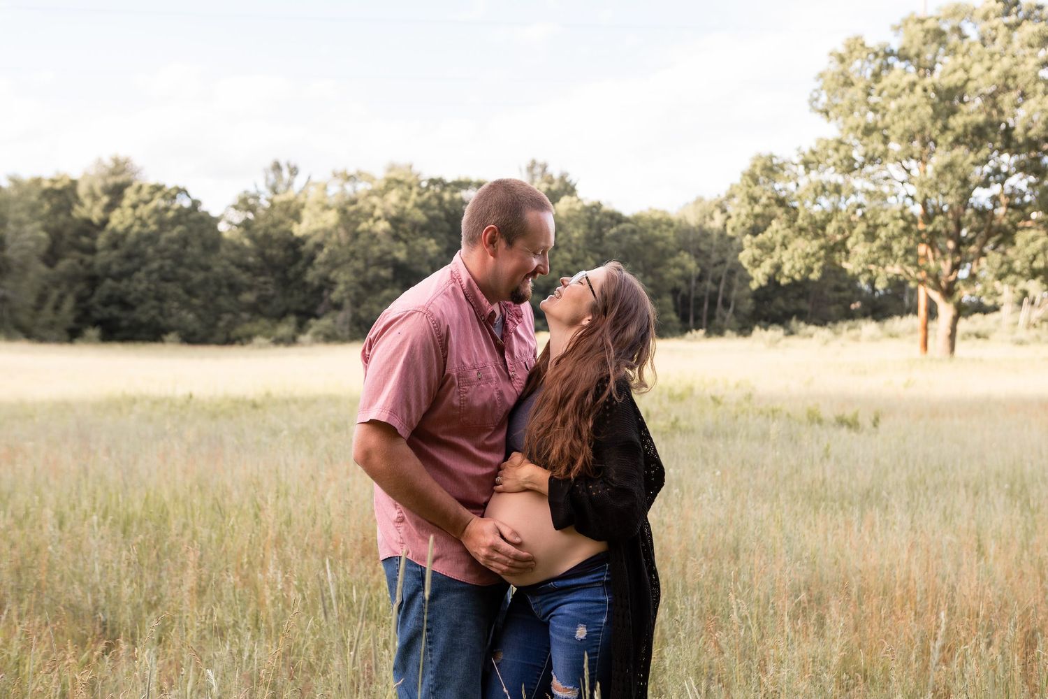 Couple embracing and smiling holding baby bum in wheat field in Columbus Ohio