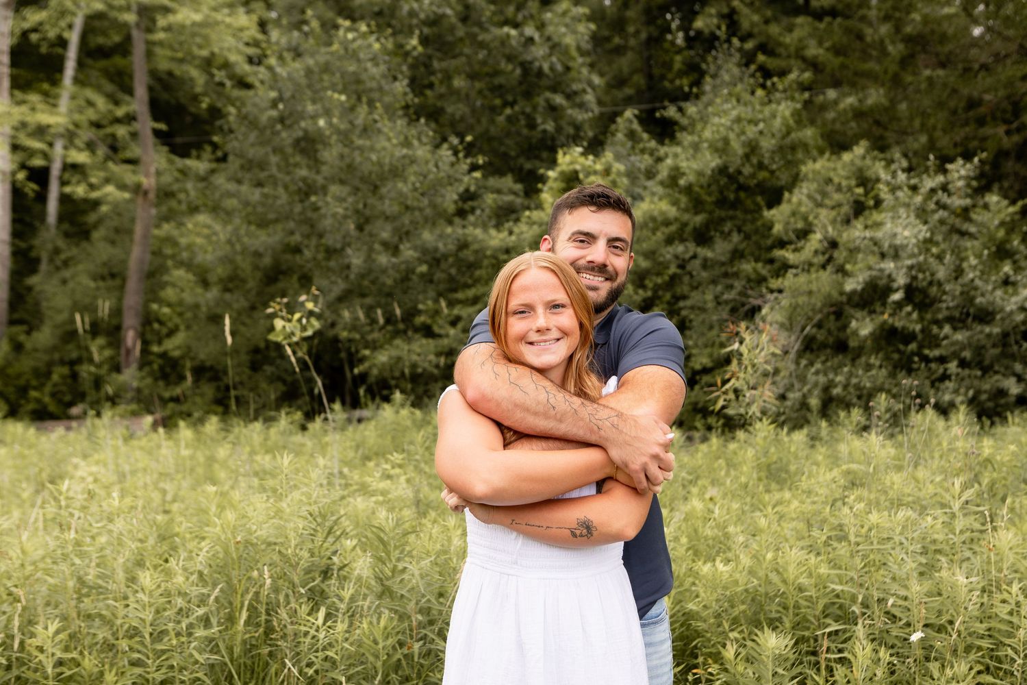 Couple hugging and smiling in grassy field in white and blue in Columbus Ohio