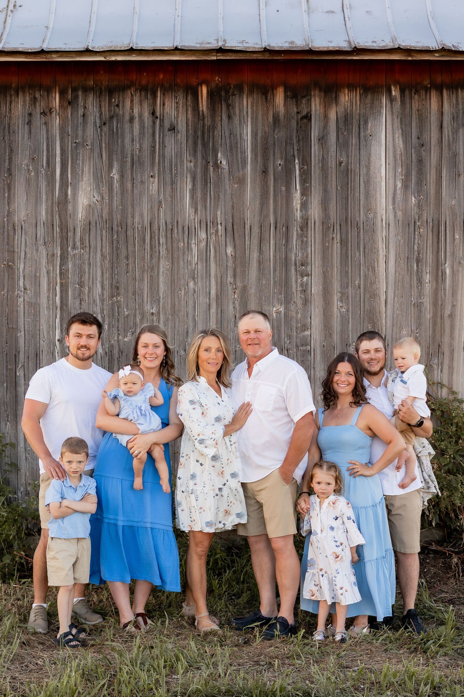 Large extended family in white and blue outfits beside barn in Columbus Ohio